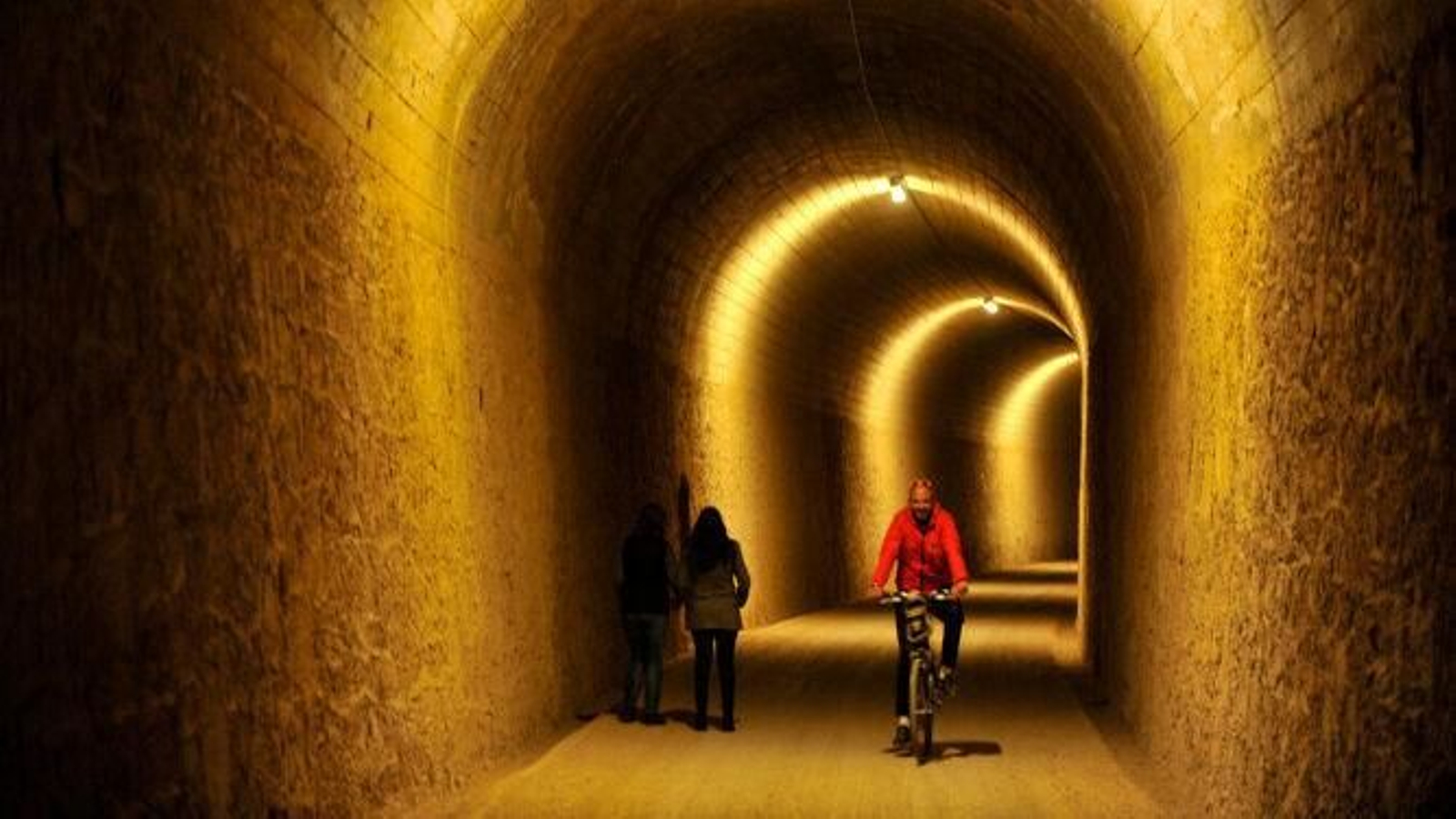 Ciclista y peatones en uno de los tuneles de la Vía Verde de la Sierra con la que pretende enlazar la ampliación hasta Jerez.