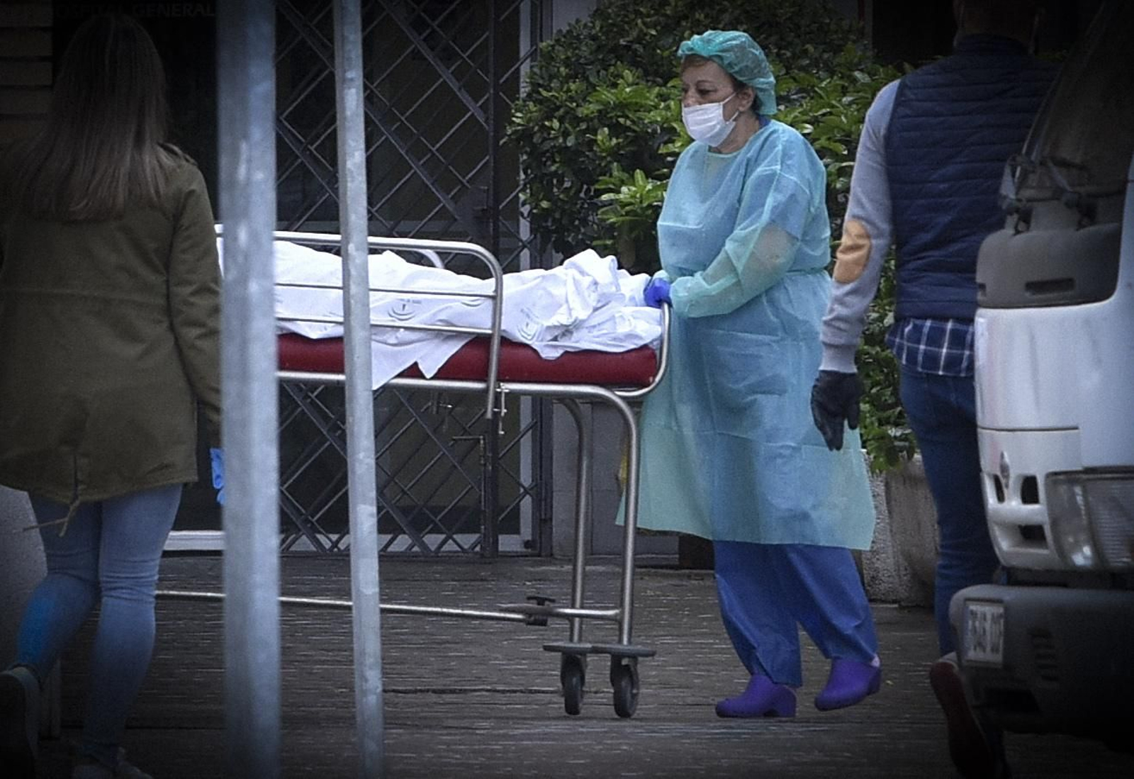 Una profesional sanitaria traslada a un enfermo en camilla.