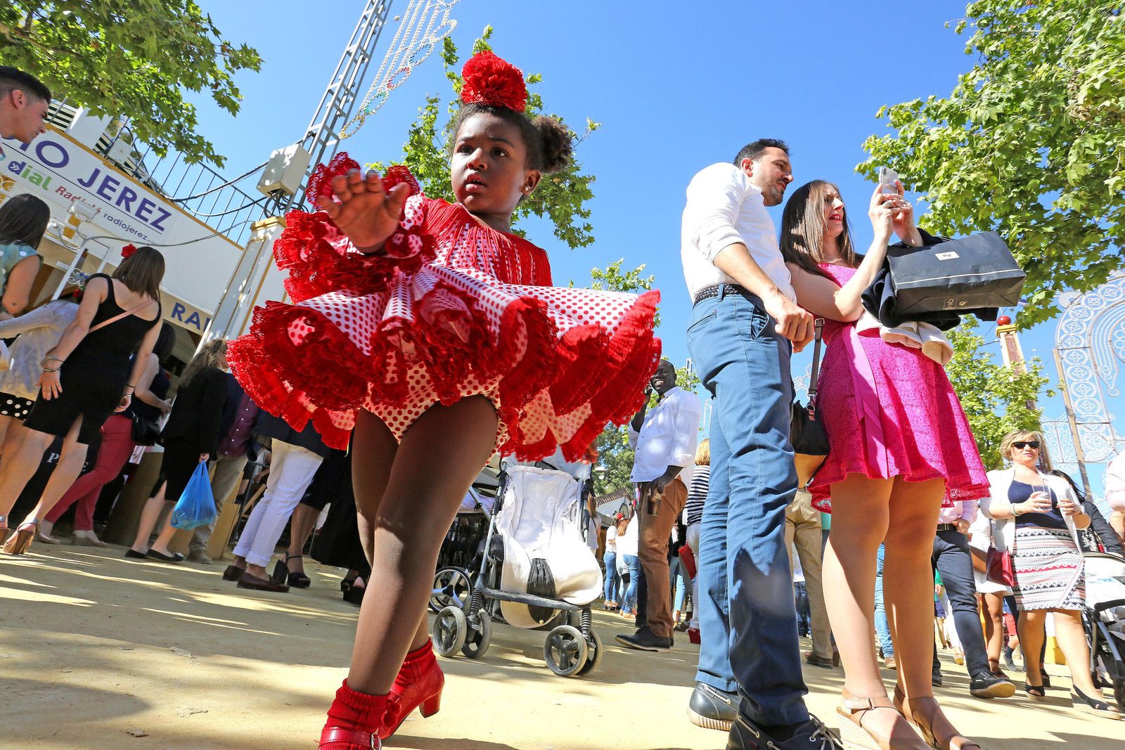 Una niña pasea orgullosa con su traje de flamenca.
