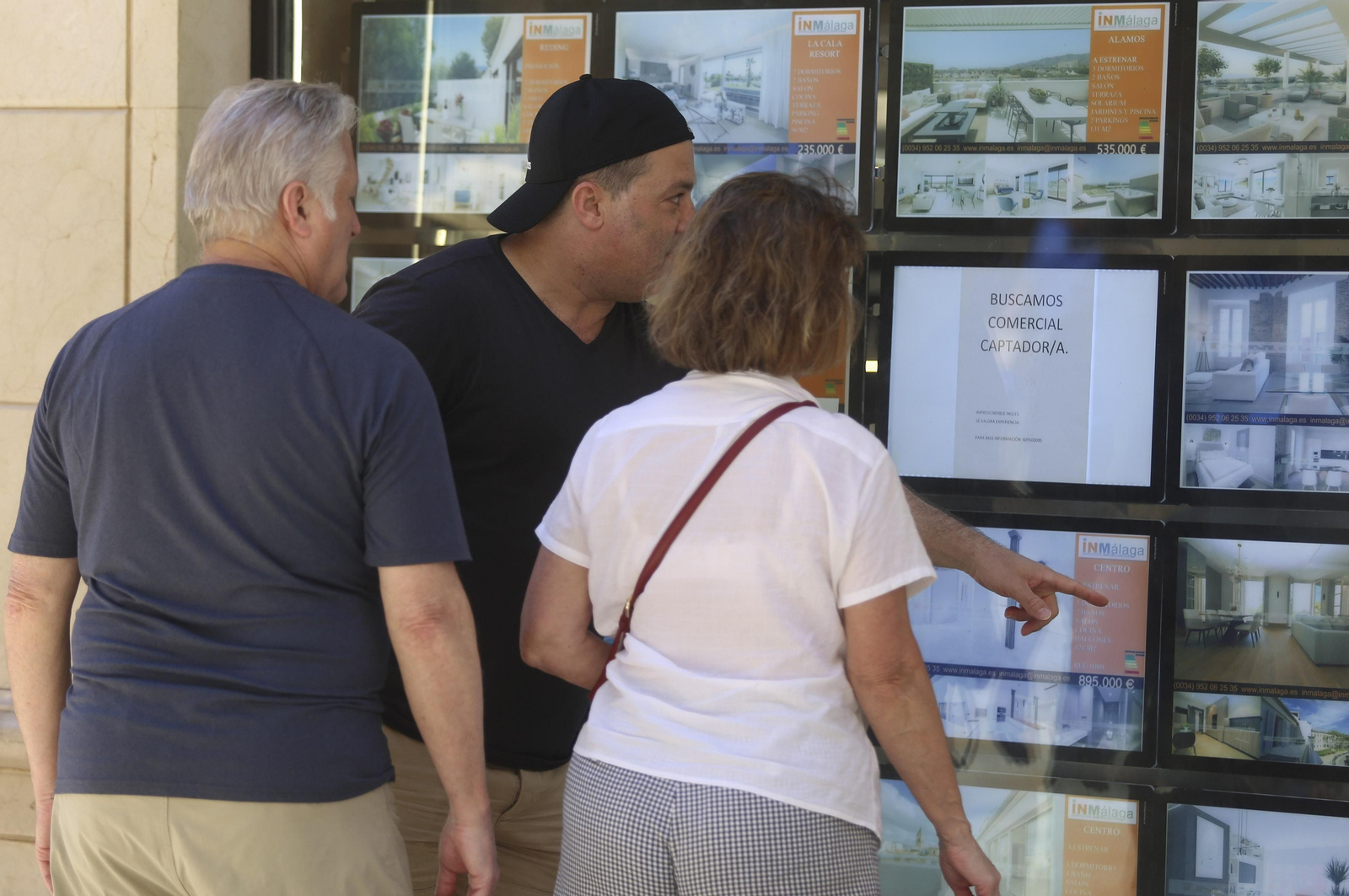 Varias personas miran los precios en una inmobiliaria de Málaga.