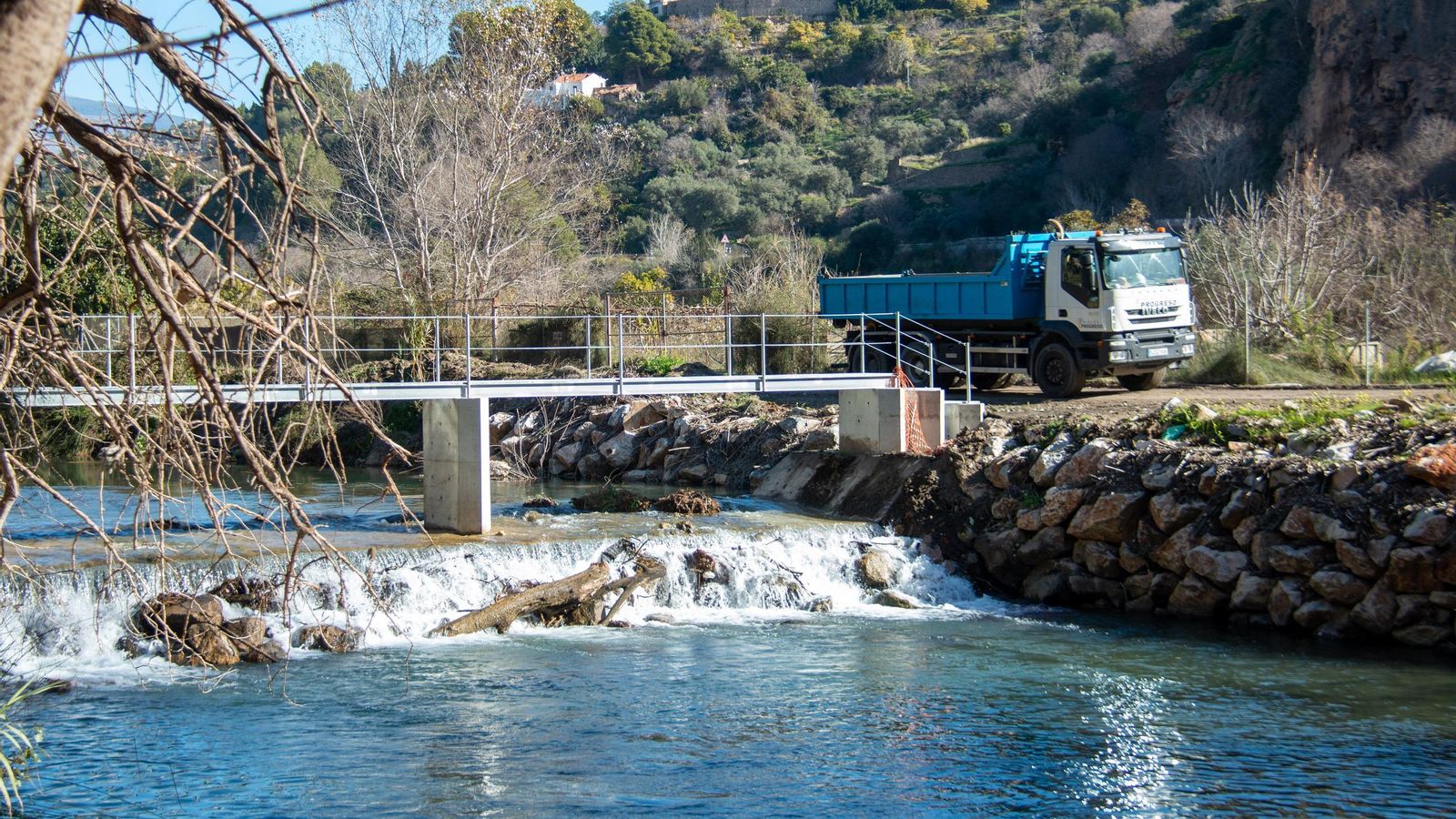 Un camión pasa por un márgen del río Guadalfeo tras transportar arena