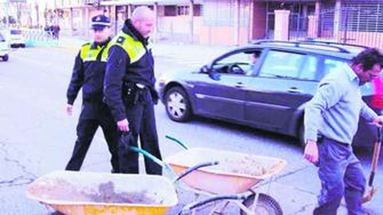 Dos policías locales observan el trabajo de un obrero que repara un bache en Doctor Fedriani.