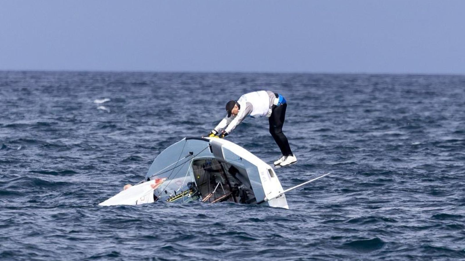 El regatista gaditano trata de adrizar la embarcación tras un vuelco. / Joaquín Carrión