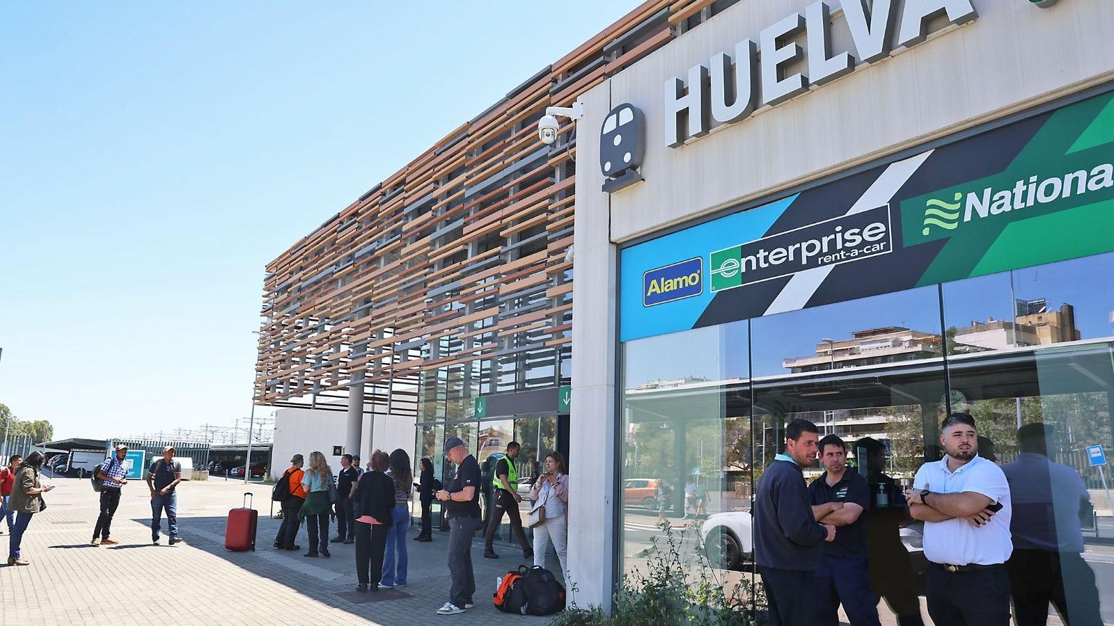 Pasajeros en la puerta de la estación de Renfe en Huelva tras ser desalojados por el apagón.