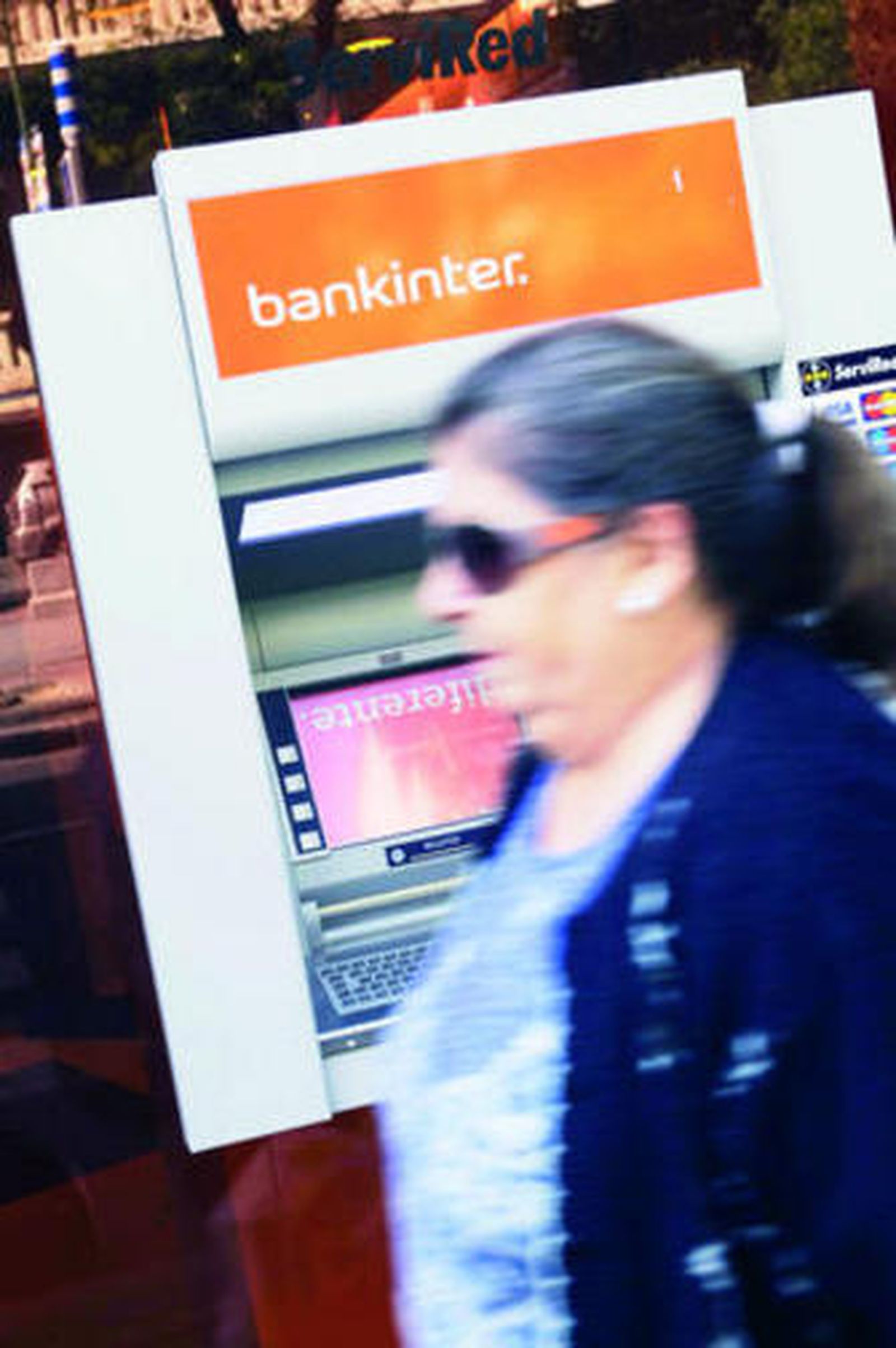 Una señora pasa por delante de un cajero de Bankinter.