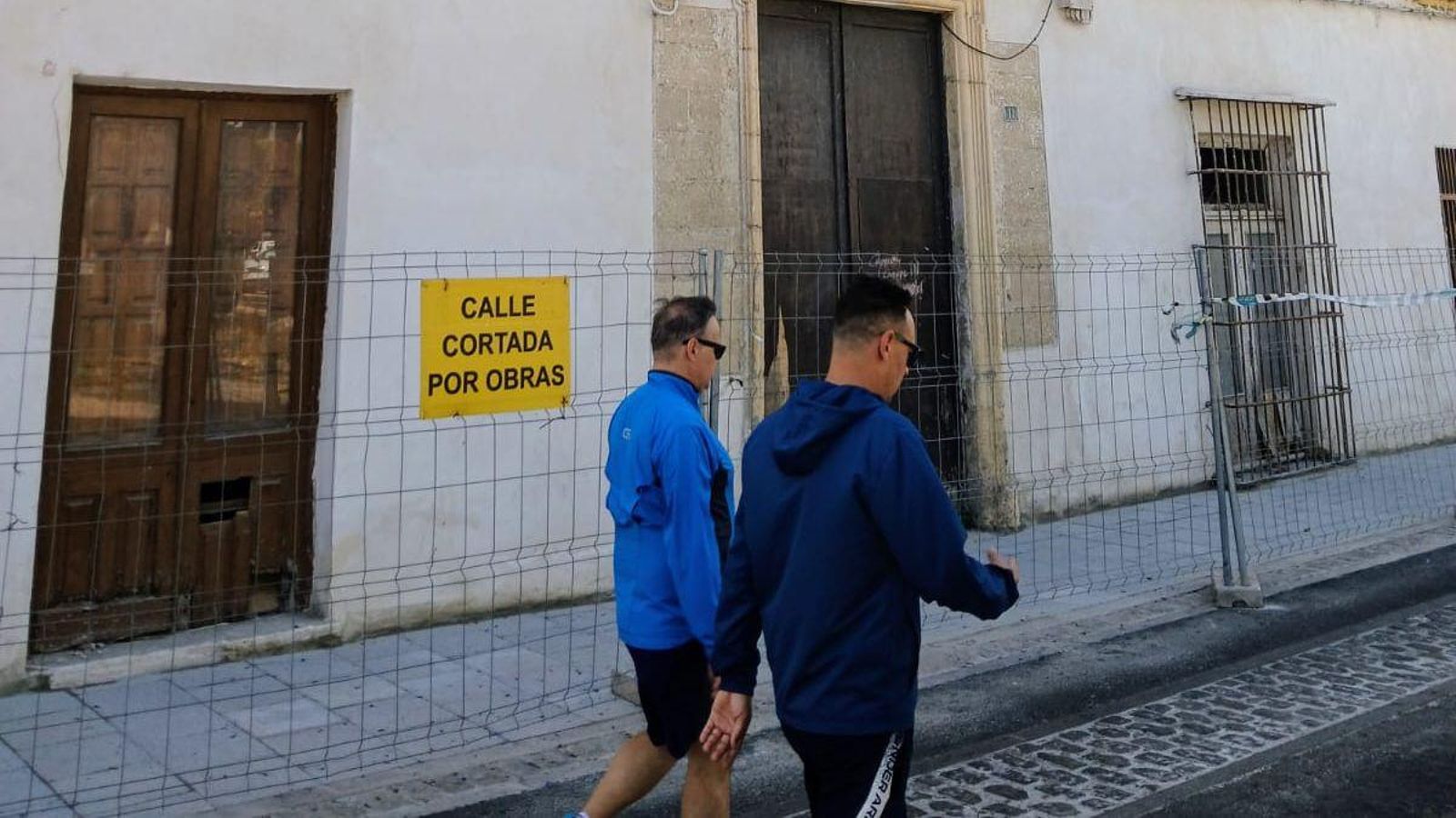 Dos transeúntes pasan frente a la puerta principal de la casa palacio de Cargadores a Indias, junto al antiguo Bar El Rempujo.