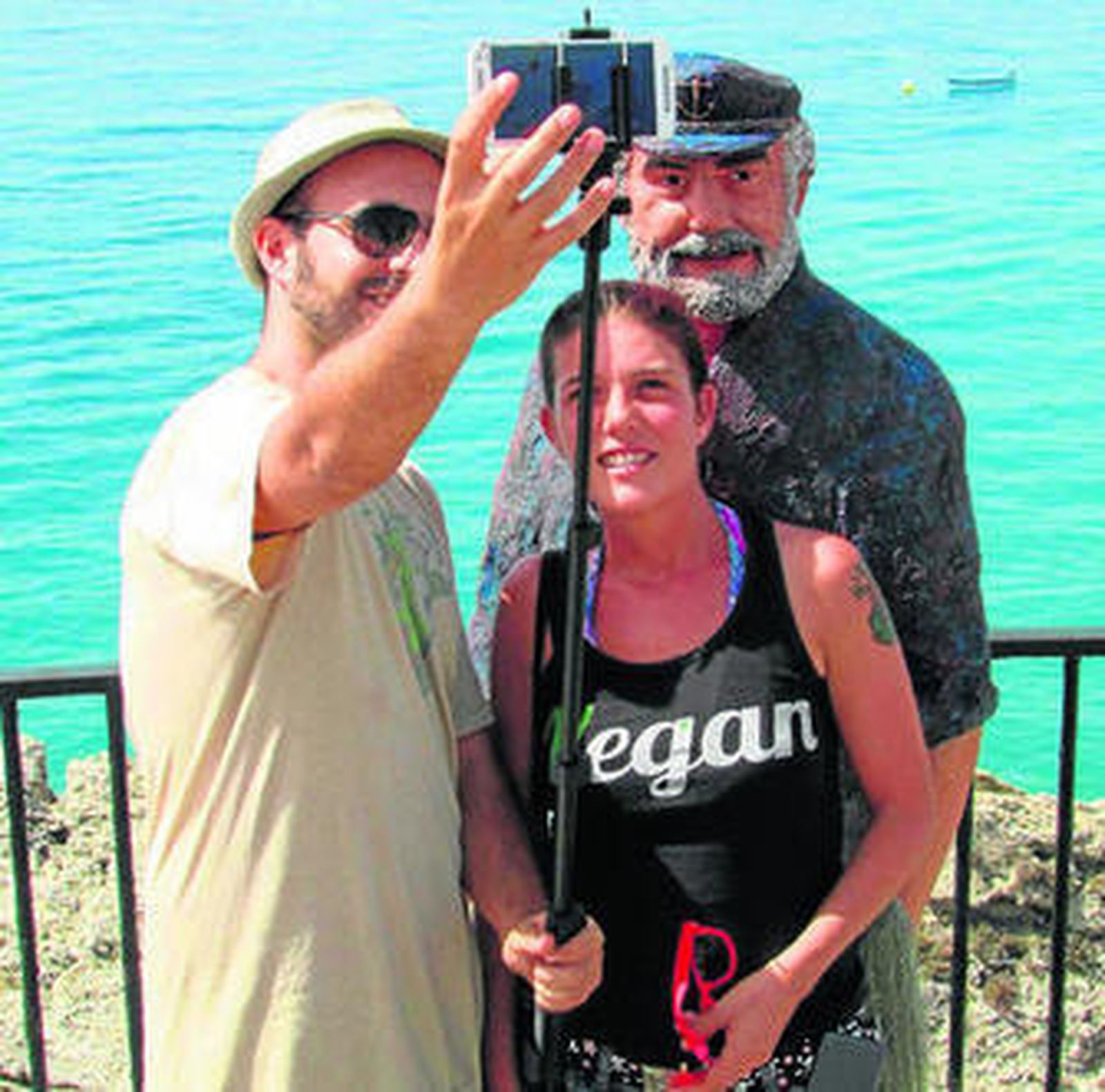 Dos personas se hacen un selfie ante la estatua.