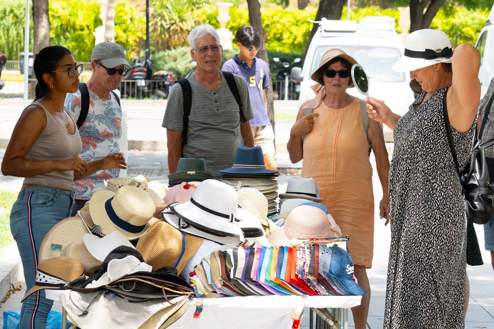 Turistas comprando sombreros para evitar el calor.