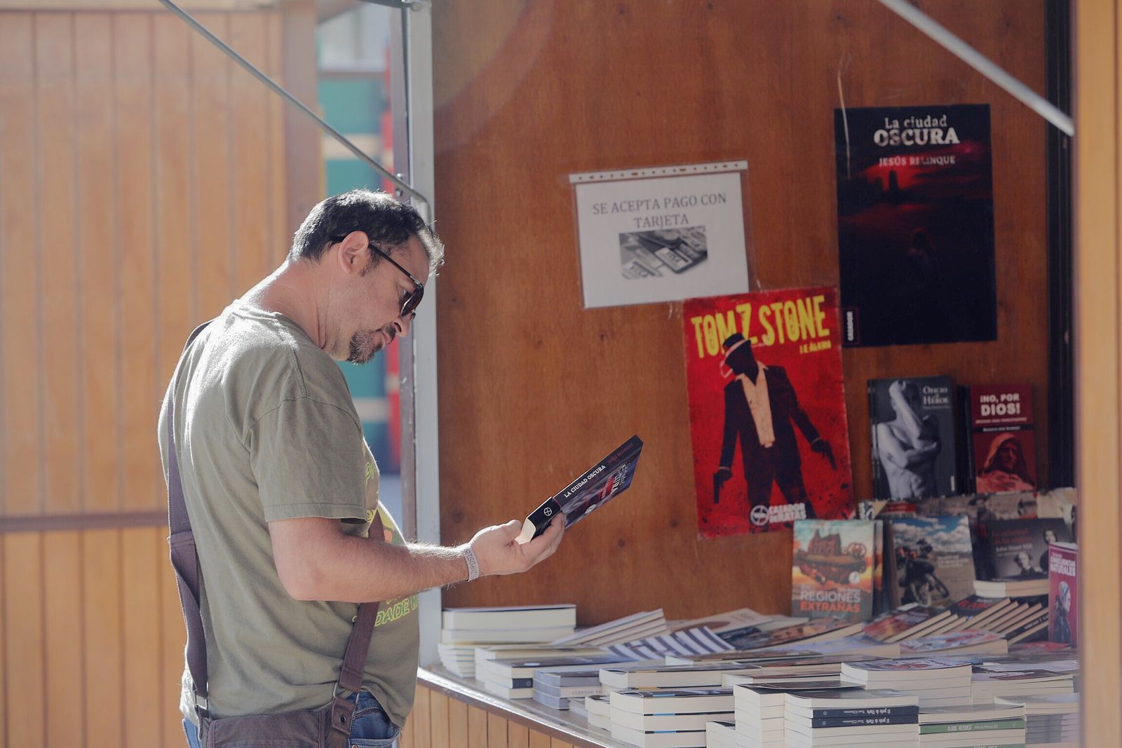 Un hombre se interesa por un libro, en uno de los expositores de la Plaza de la Iglesia.