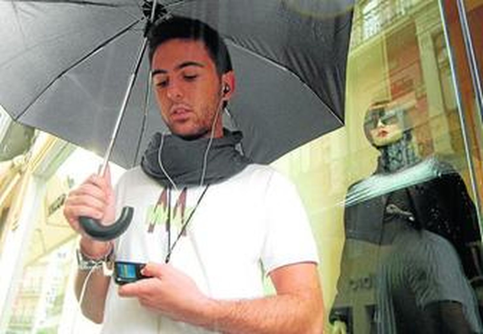 Un joven escucha música con un reproductor MP3 por una céntrica calle de Sevilla.