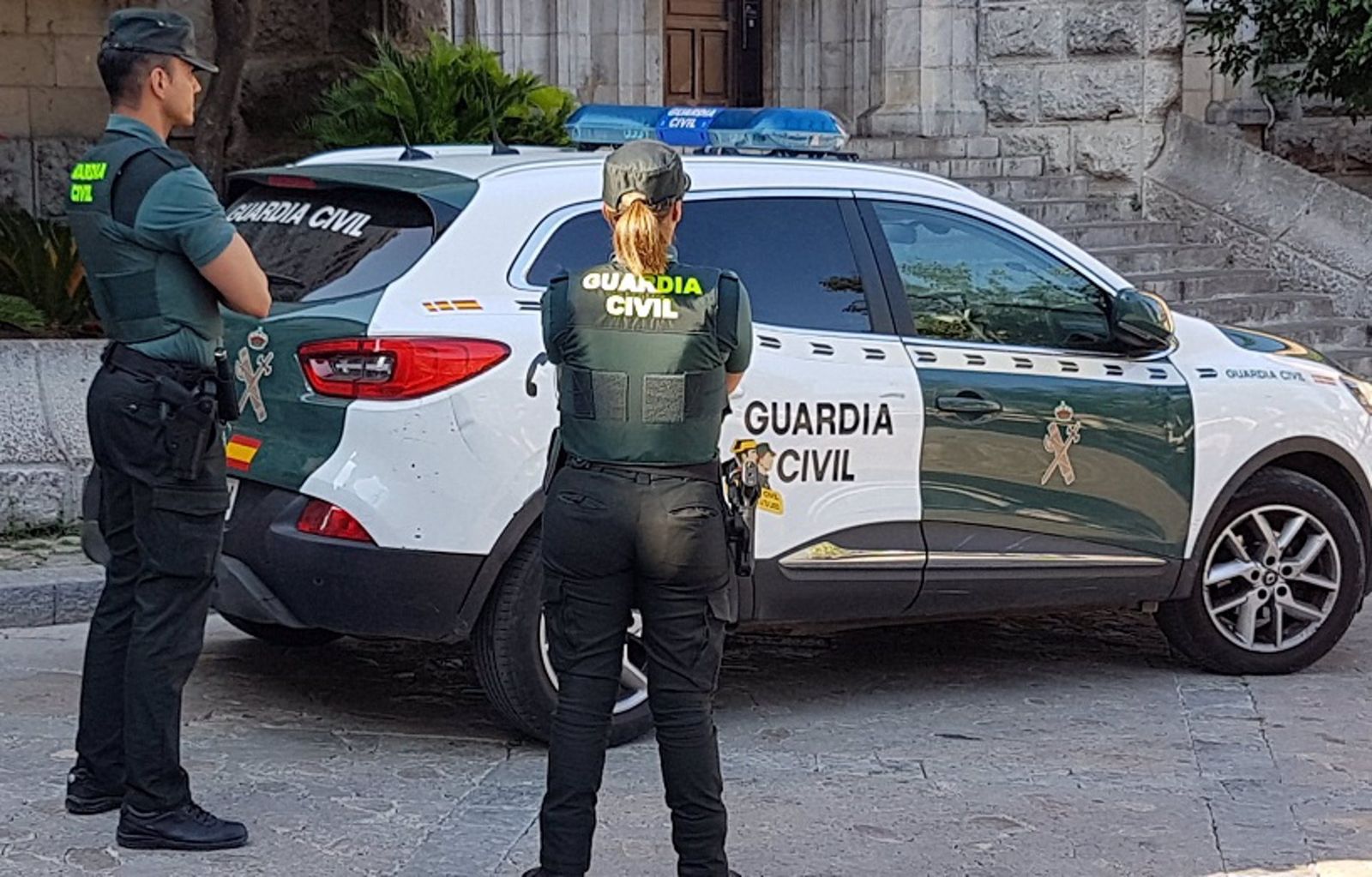 Dos agentes de la Guardia Civil junto a un coche oficial, en imagen de archivo