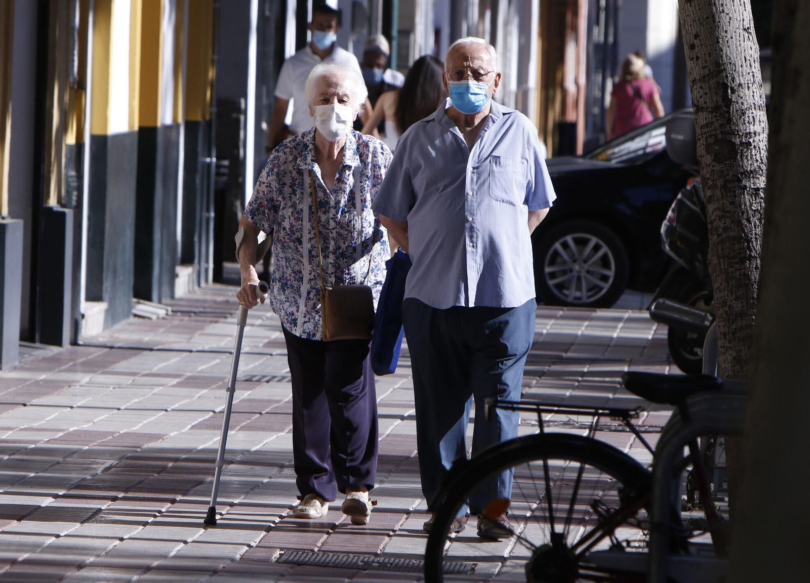 Dos personas mayores caminan protegidos con mascarillas.