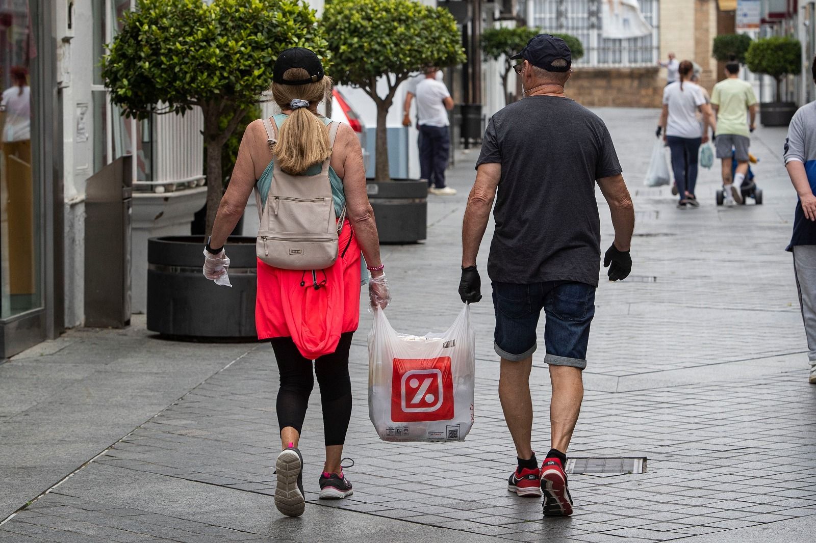 Dos ciudadanos cargan con una bolsa de compra por el centro de San Fernando.