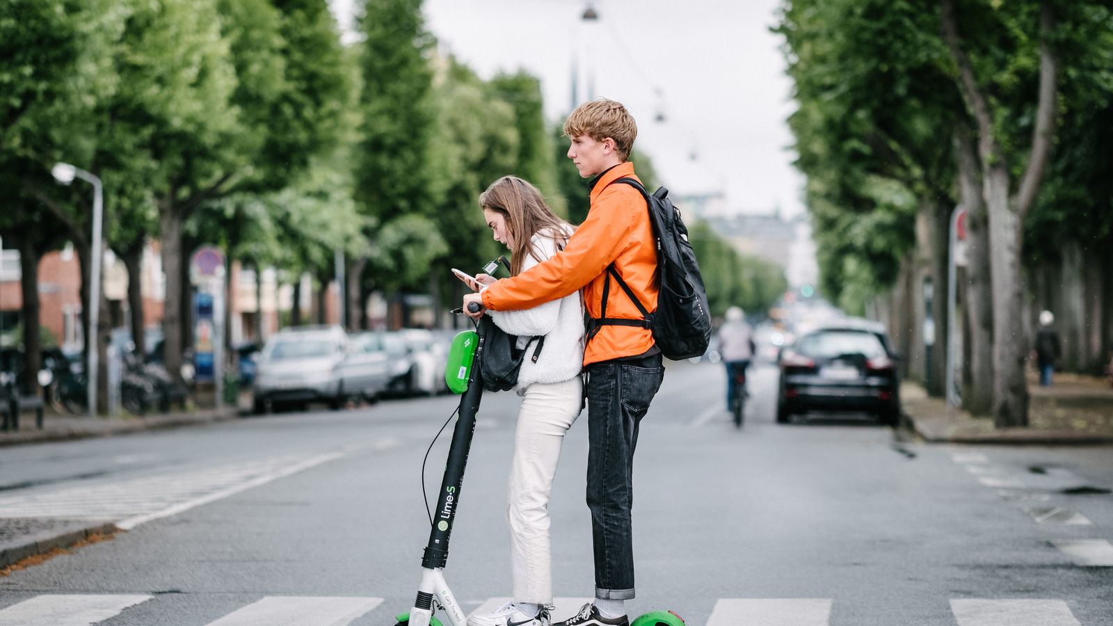 Imagen de dos jóvenes en un patinete eléctrico.