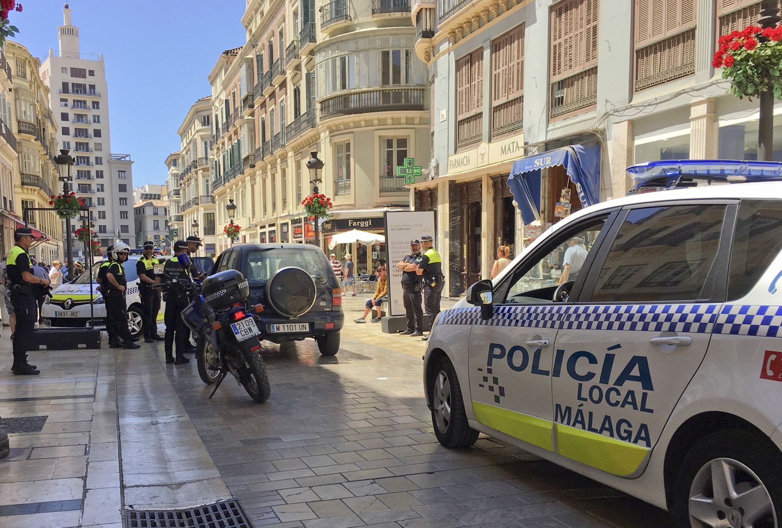 El vehículo en medio de la calle Larios rodeado por la Policía Local.