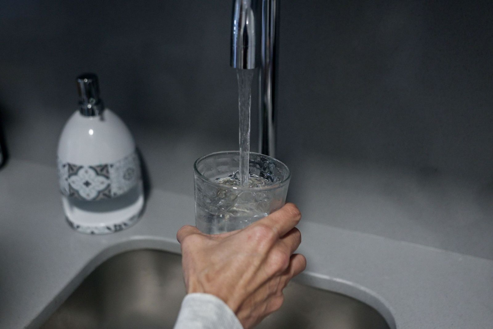 Una persona llena un vaso de agua.