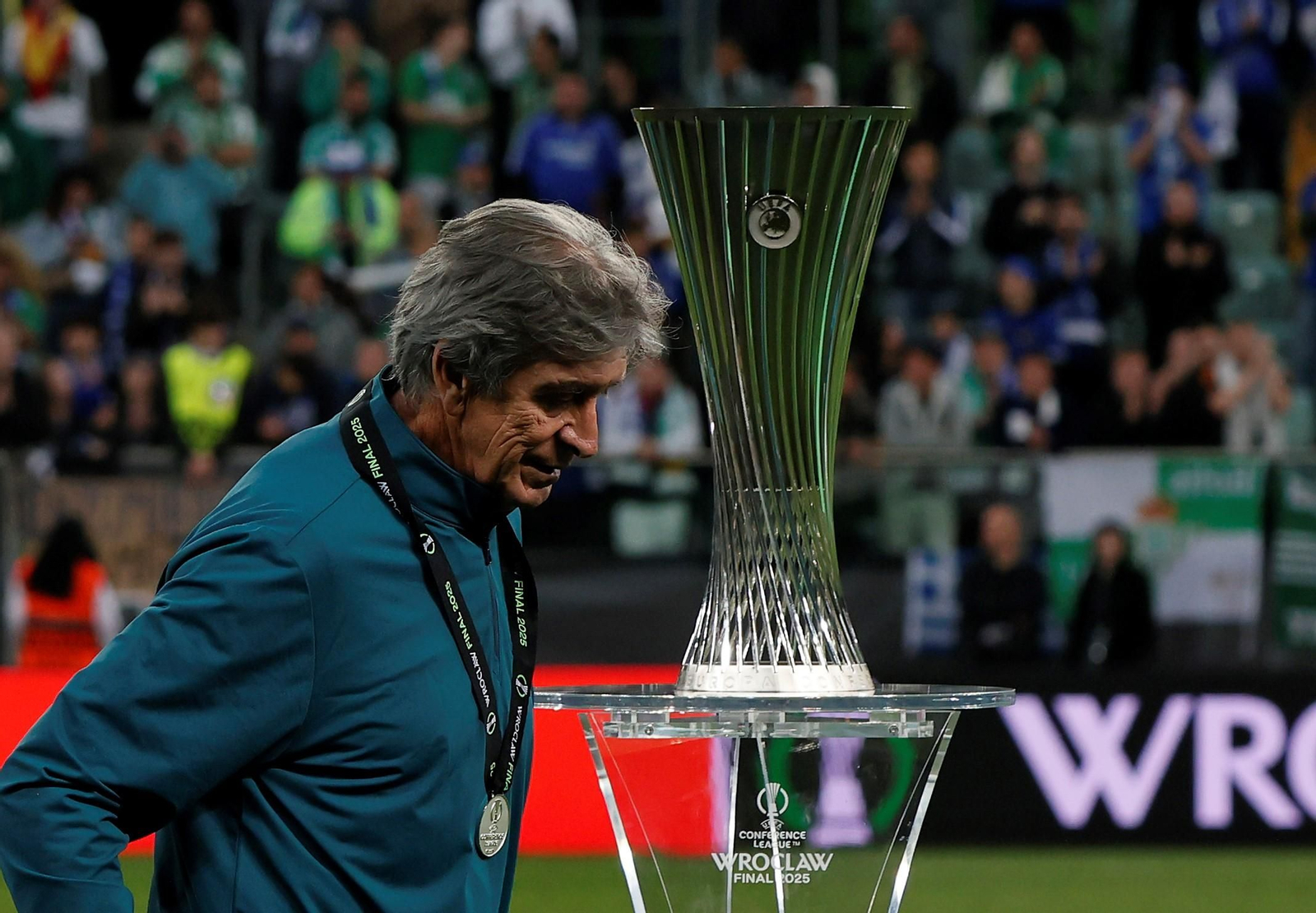 Pellegrini mirando hacía abajo y de fondo el título de la Conference League