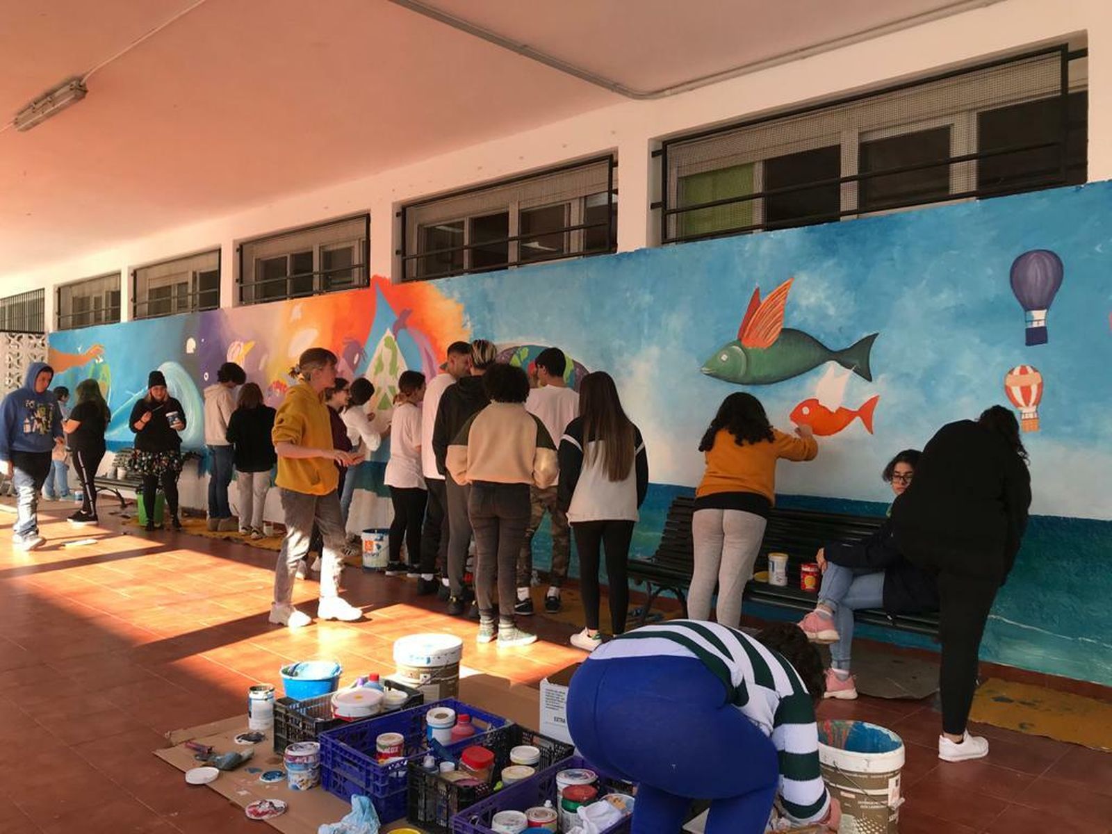 Los jóvenes durante la elaboración del mural en una de las paredes del centro educativo.