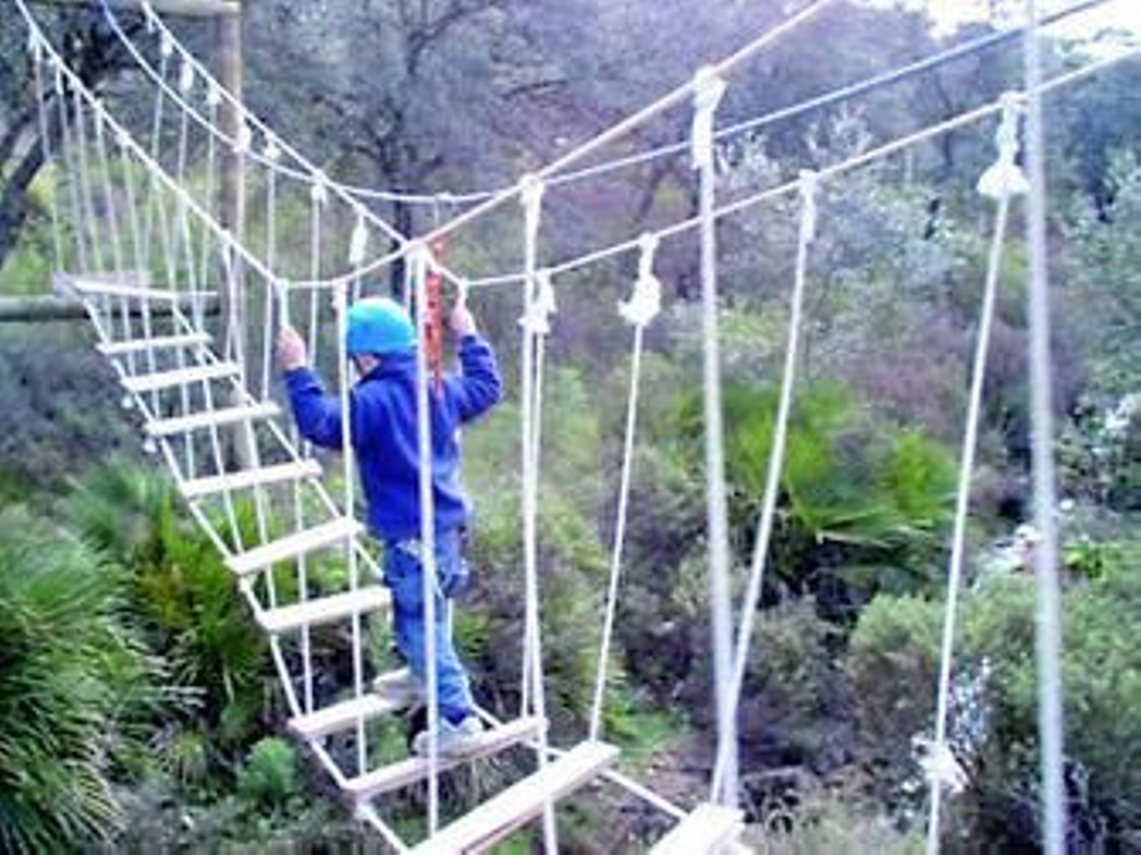 Un niño pasa un puente colgante en El Encinar de Escardiel durante un campamento de verano.