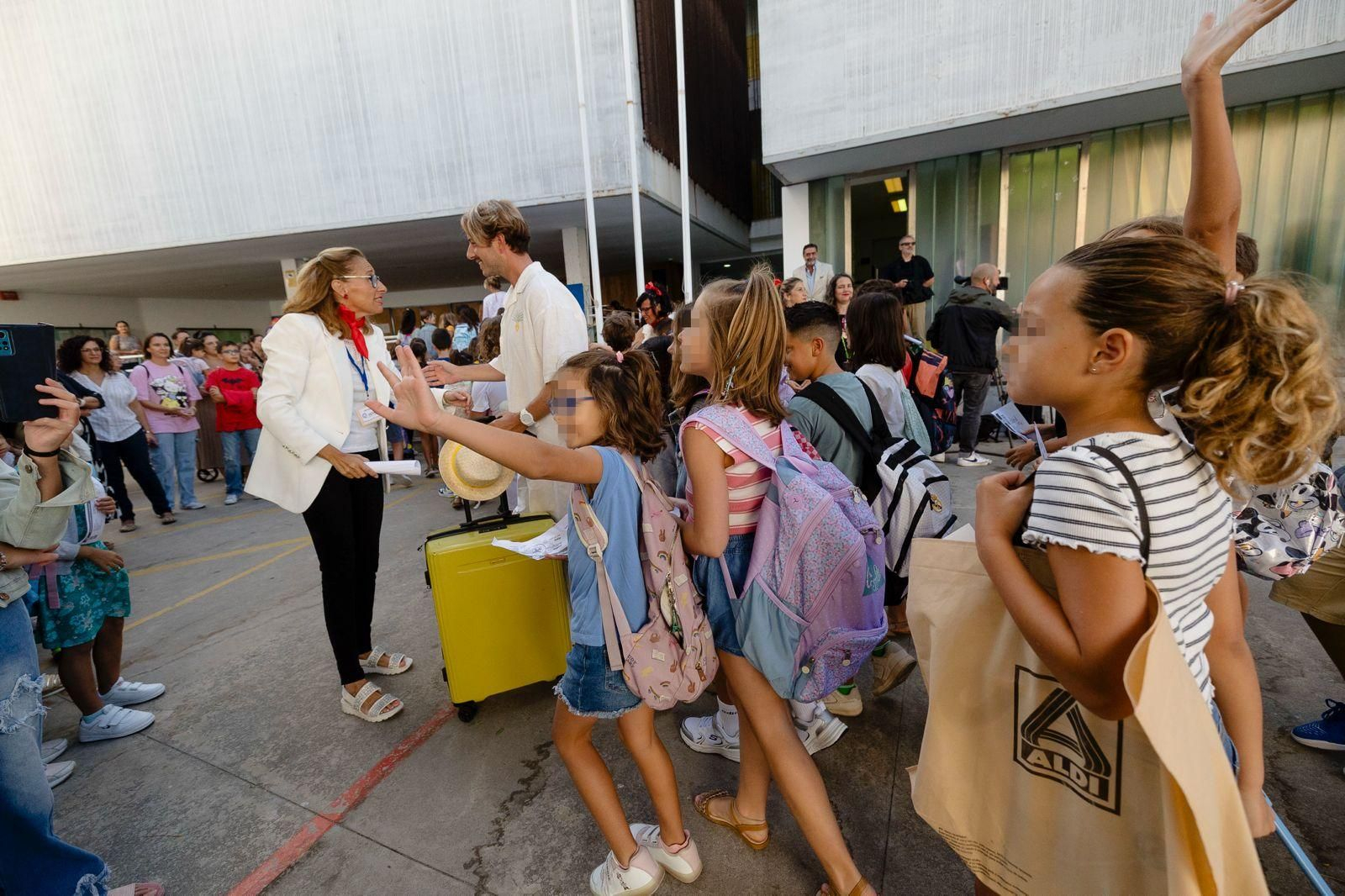 Un profesor con maleta de viaje es seguido hacia la clase por sus alumnos.