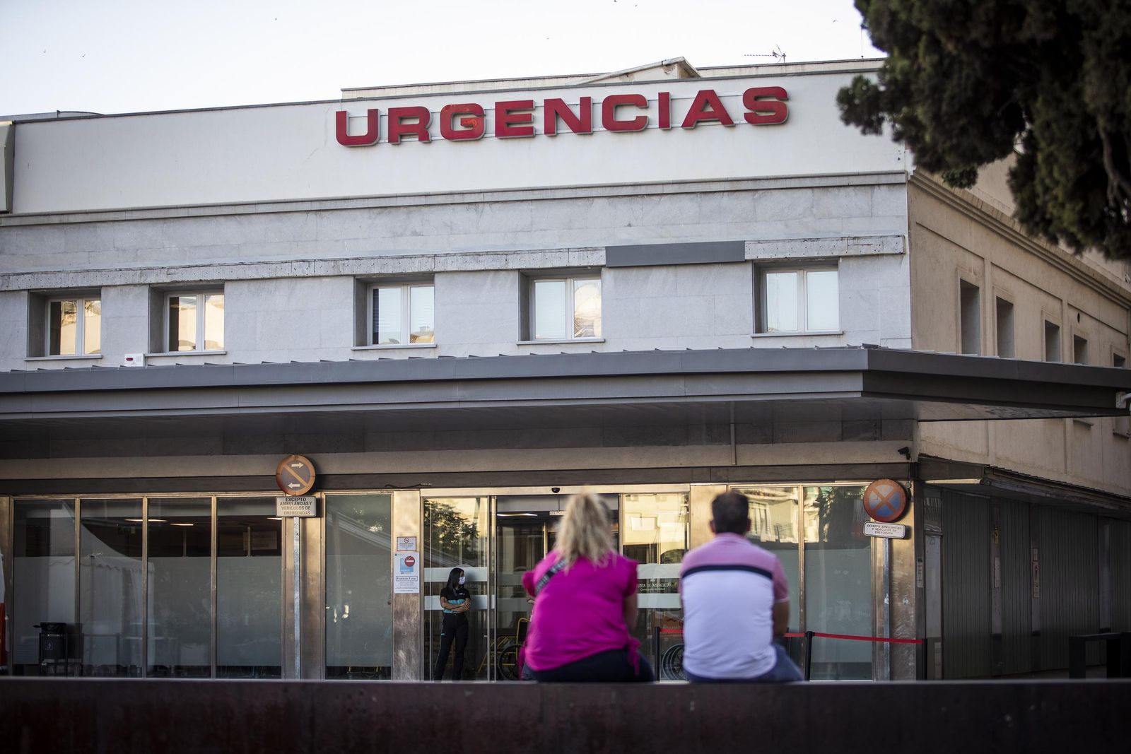 Dos personas esperan ante la entrada de Urgencias de un hospital de Granada.