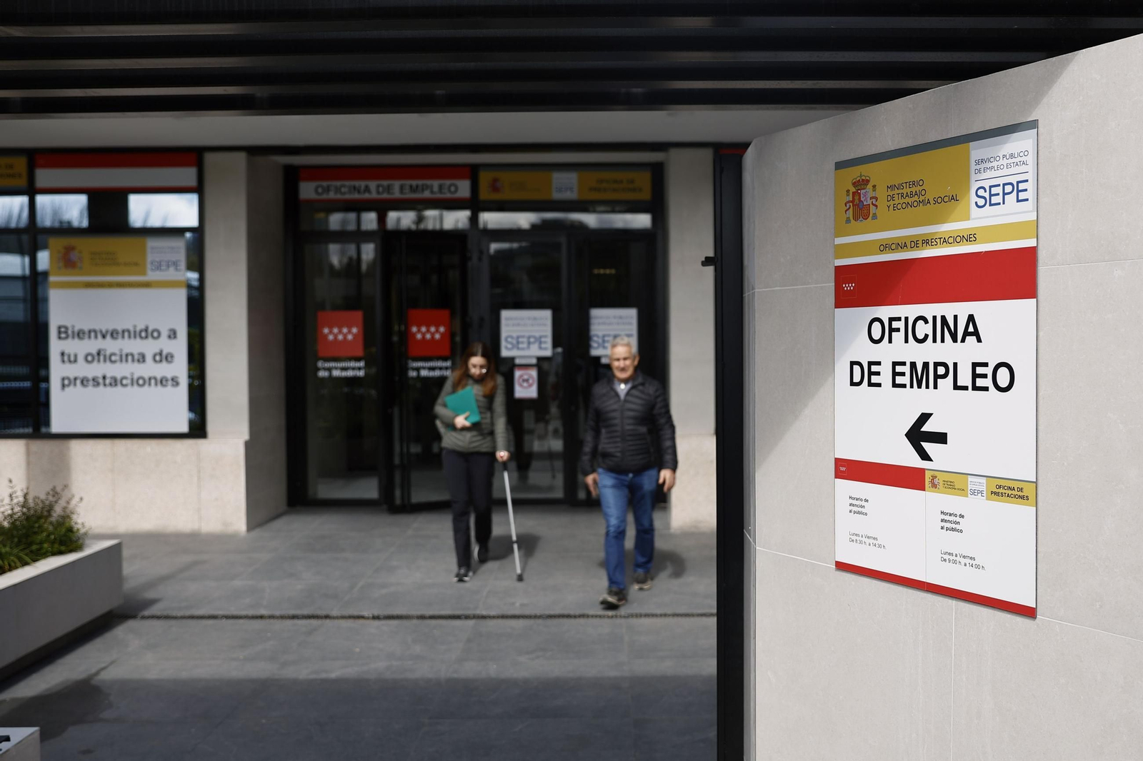Dos personas salen de una oficina de empleo.