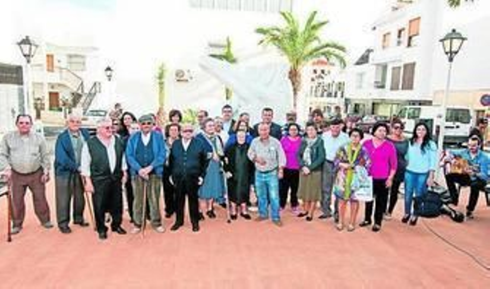 El alcalde y el escultor junto a los vecinos posan delante de la escultura.