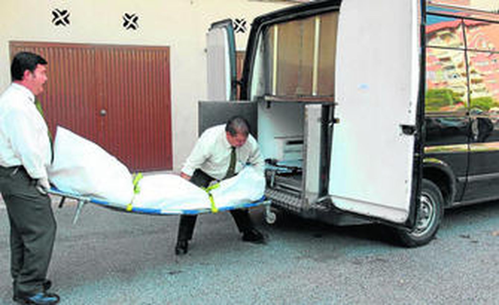 Operarios de una funeraria trasladan el cadáver de la mujer fallecida.