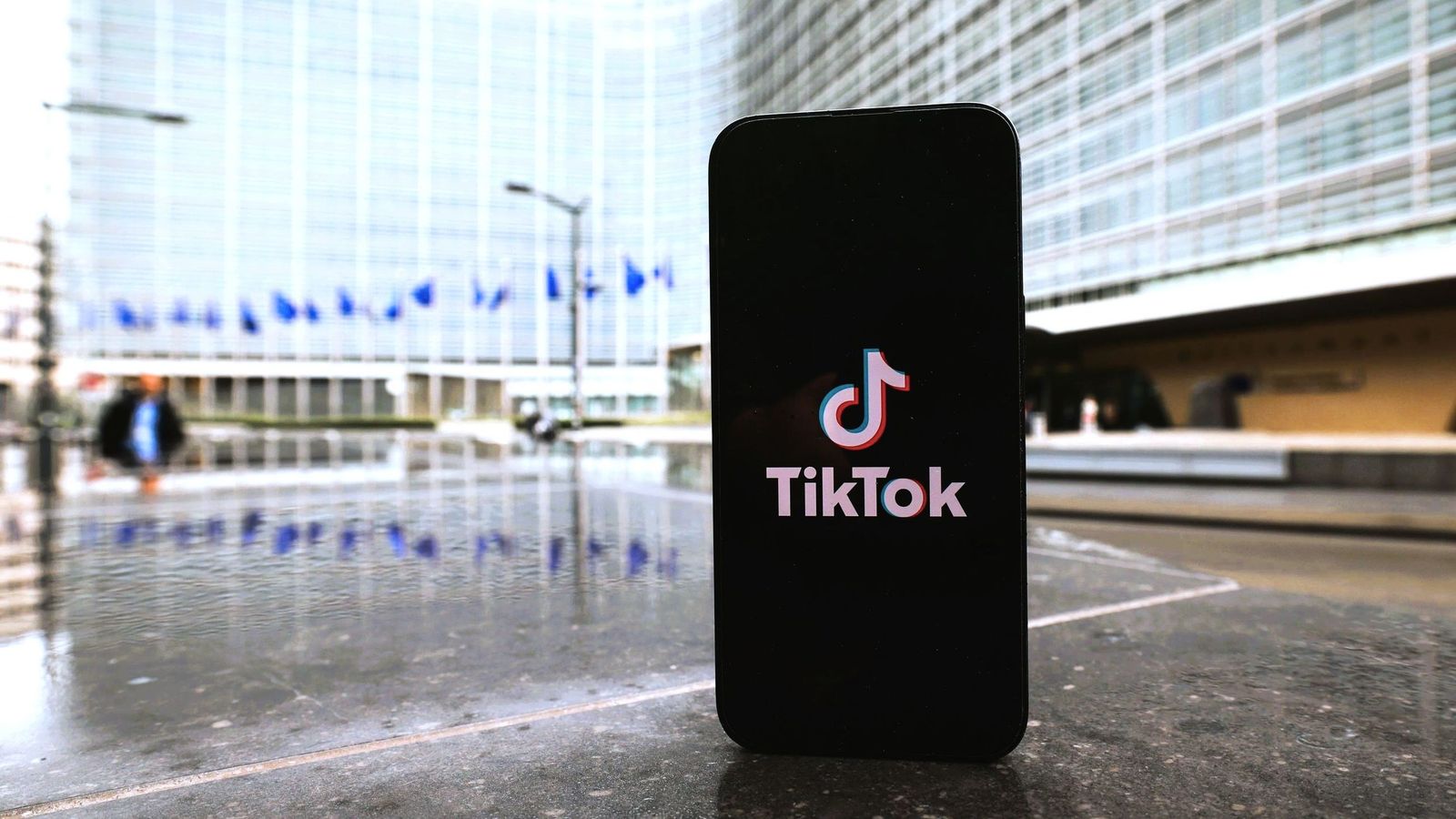 Un teléfono móvil con el logo de Tik Tok, ante la sede de la Comisión Europea.