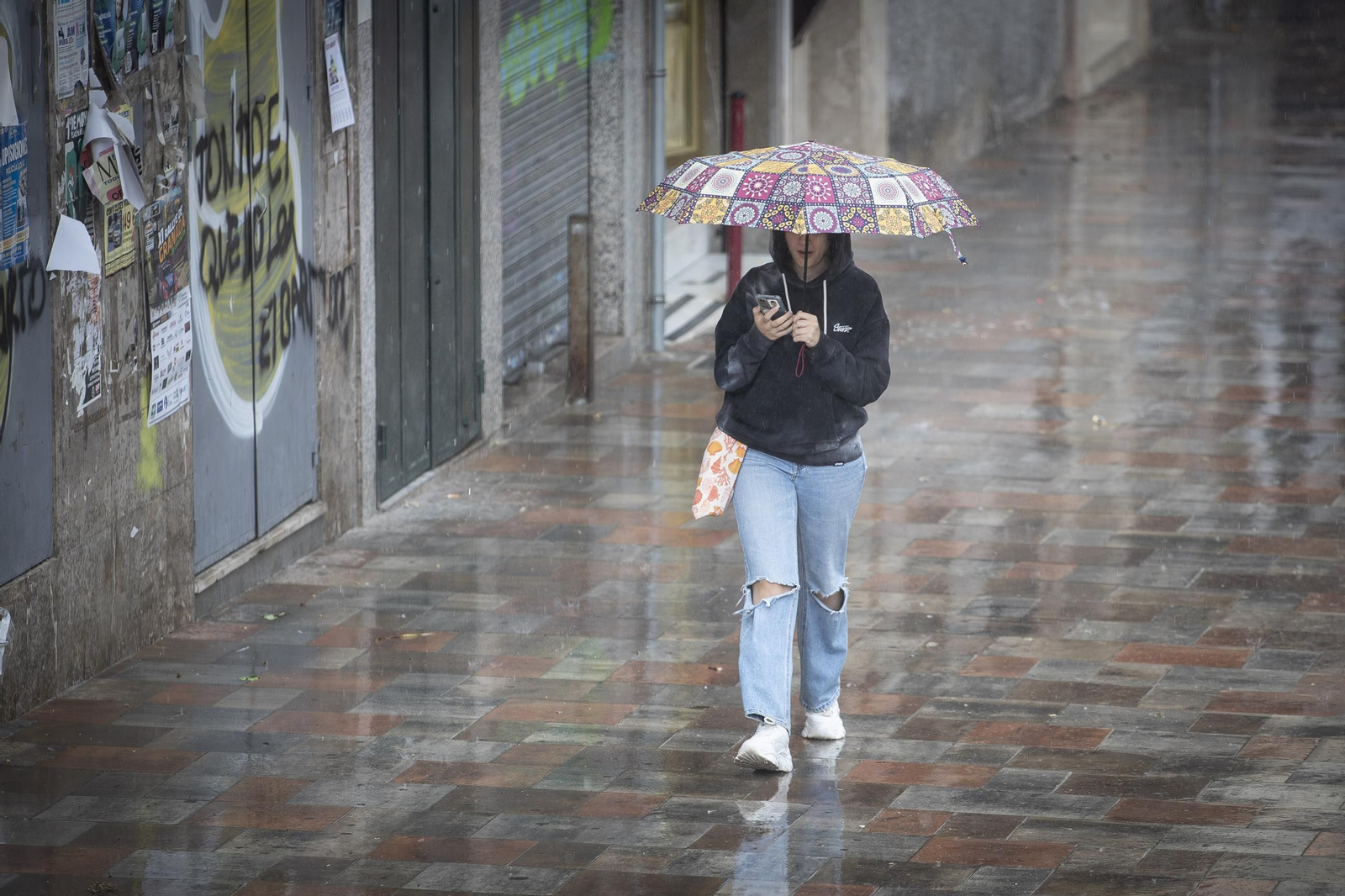 Una joven camina bajo la lluvia en Granada