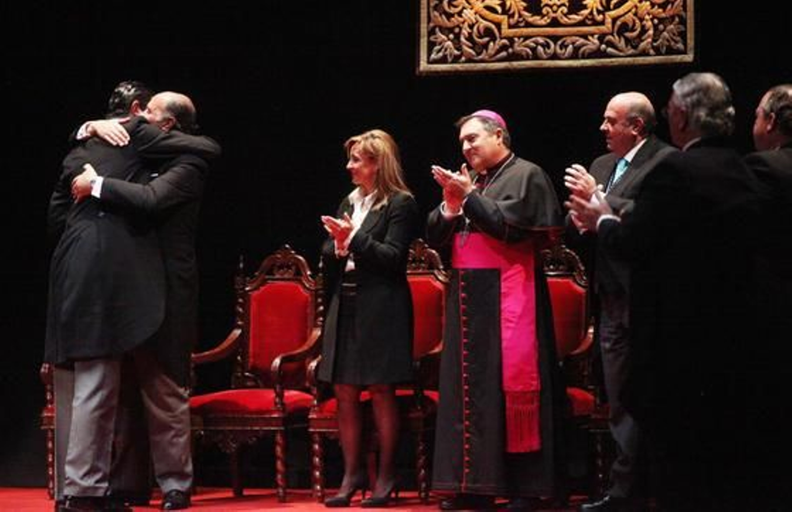 Abrazo entre pregonero y presentador, padre e hijo, al final del acto, junto a la alcaldesa, el obispo y el presidente del Consejo.

Foto: Vanesa Lobo