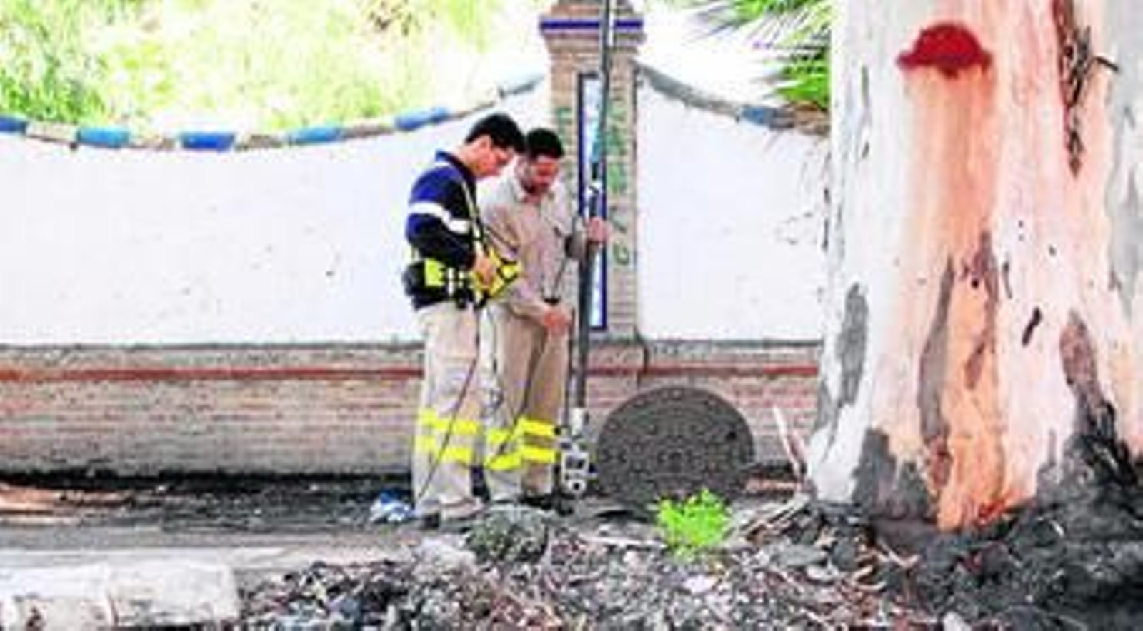 Dos operarios de Emasa inspeccionan la dimensión de las raíces de los árboles en la zona de los Baños del Carmen.