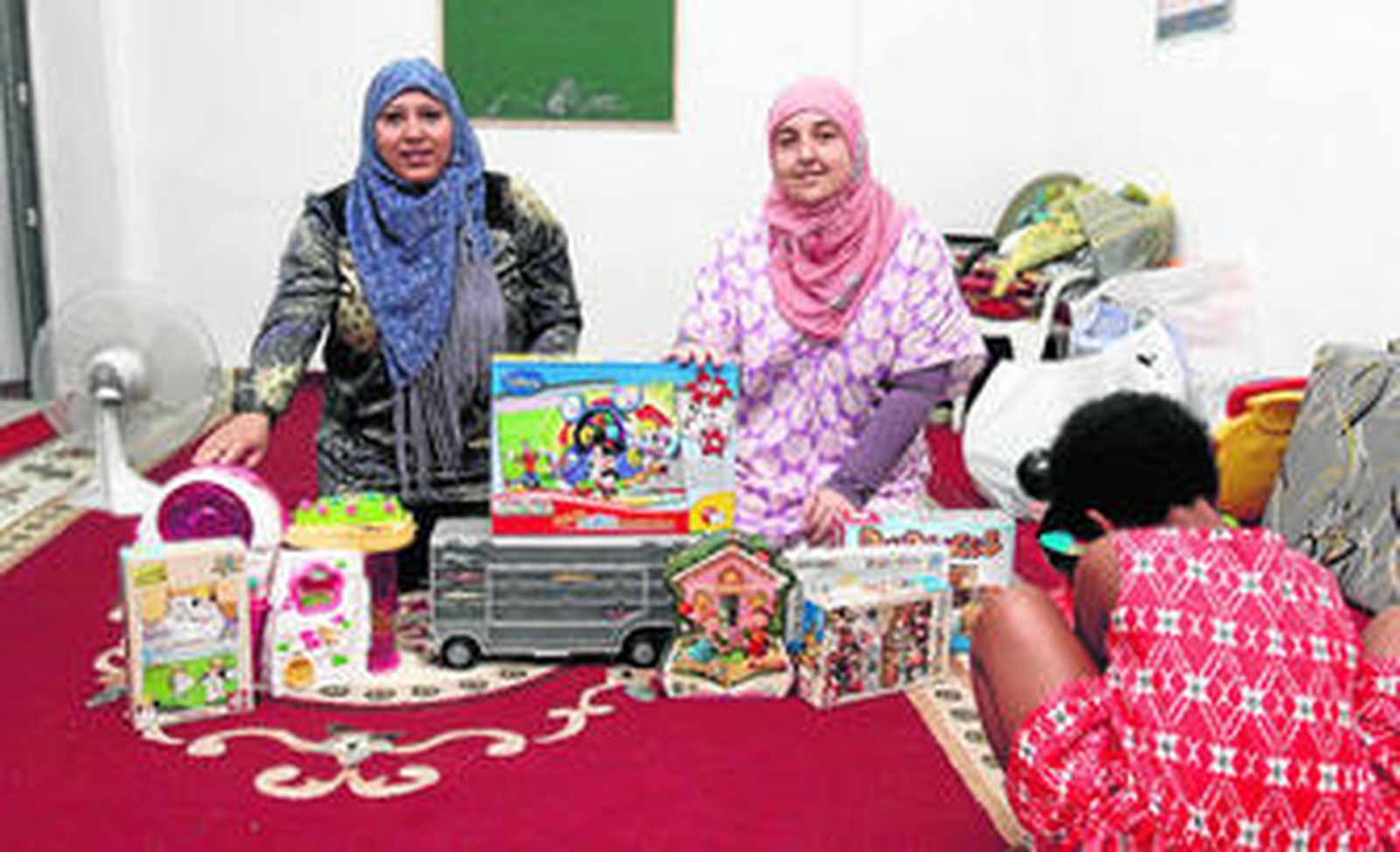 Yesenia Menéndez y Fátima Roldán posan en la mezquita Ishbilia con algunos de los juguetes que repartirán mañana.