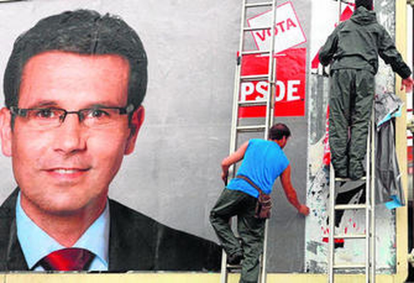 Varios operarios instalan carteles de un candidato socialista con vistas al próximo día 22.