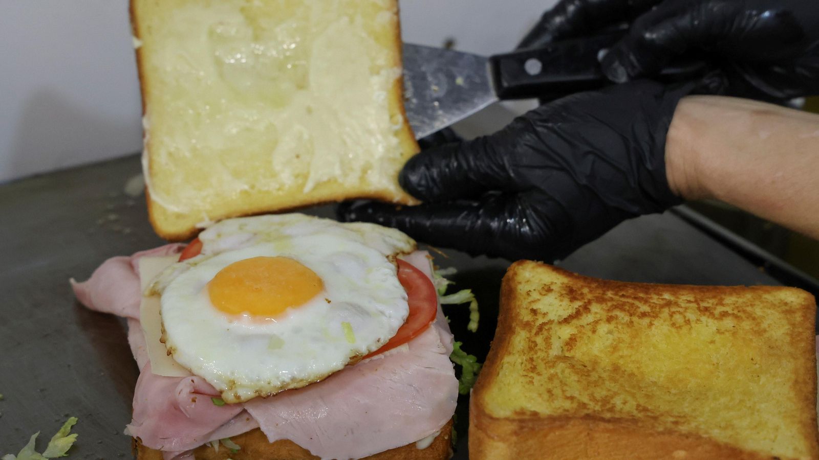 Preparando un sándwich mixto con huevo frito.