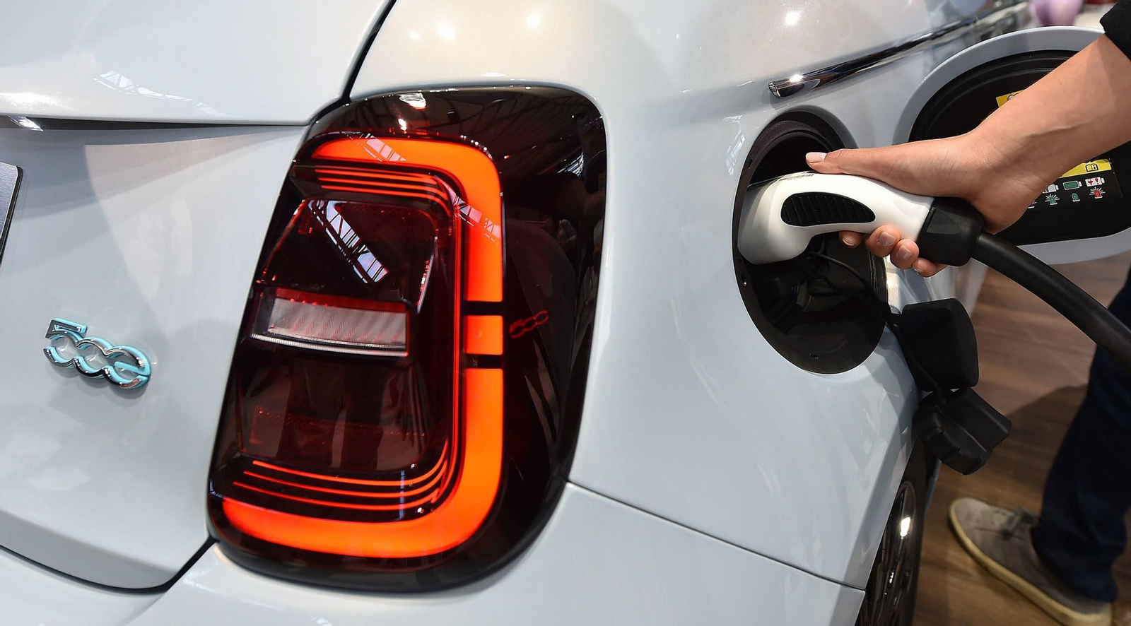 Imagen de archivo de una persona enchufando su coche eléctrico a la red