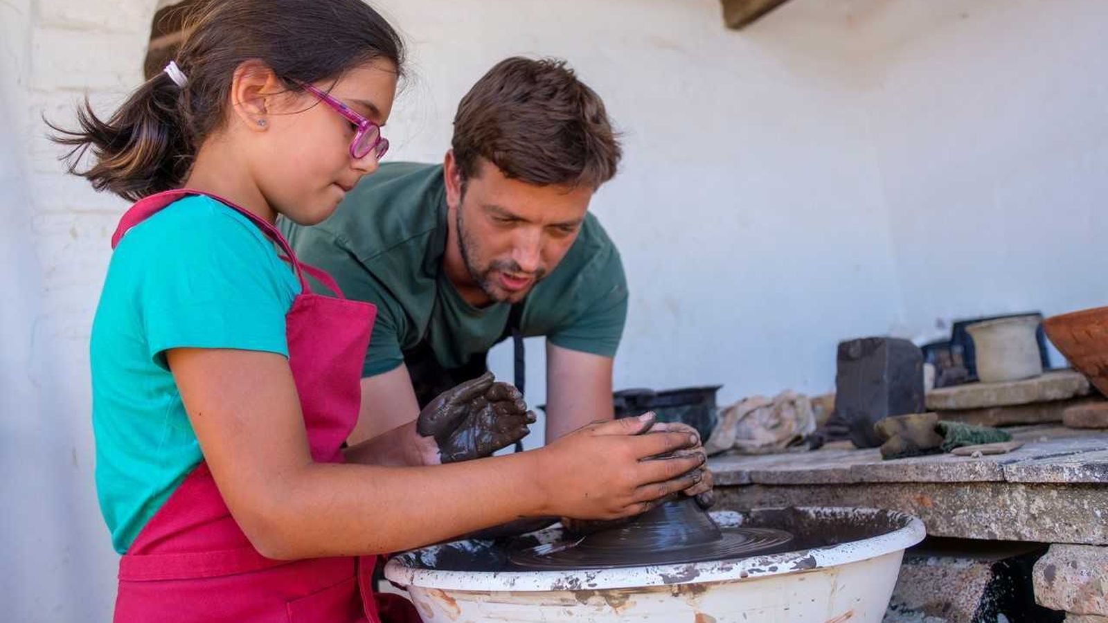 Una niña aprende en el taller de alfarería.