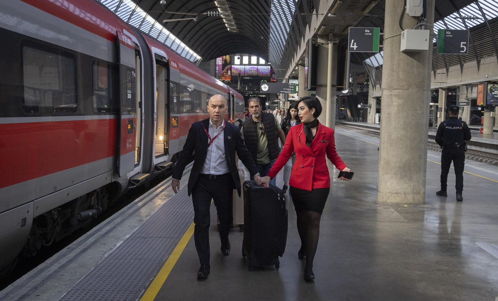 Gorini y una asistente llevan una maleta de un pasajero hasta otro vagón en Santa Justa.