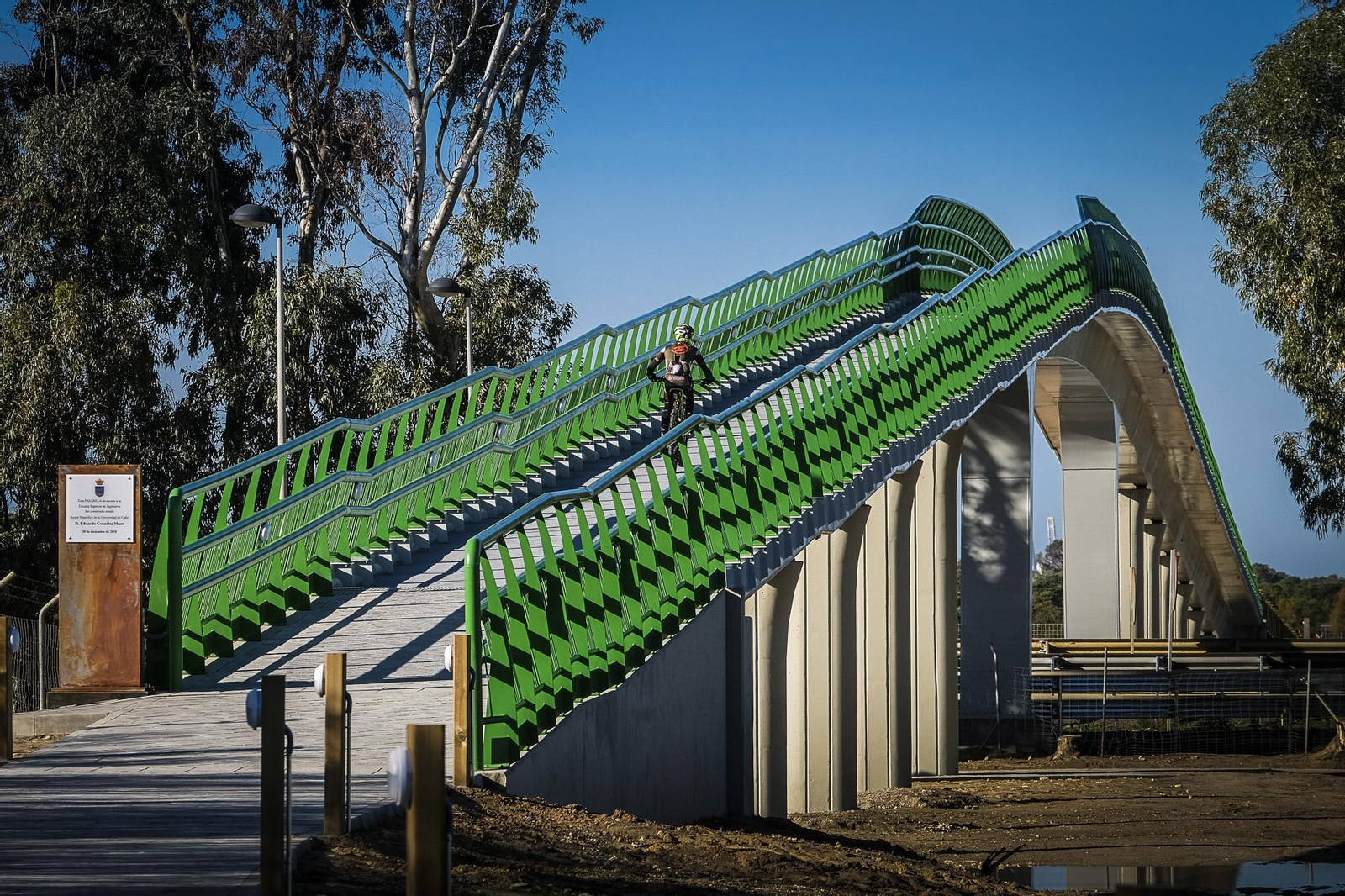Un ciclista cruzando la pasarela en dirección a la Escuela Superior de Ingeniería.