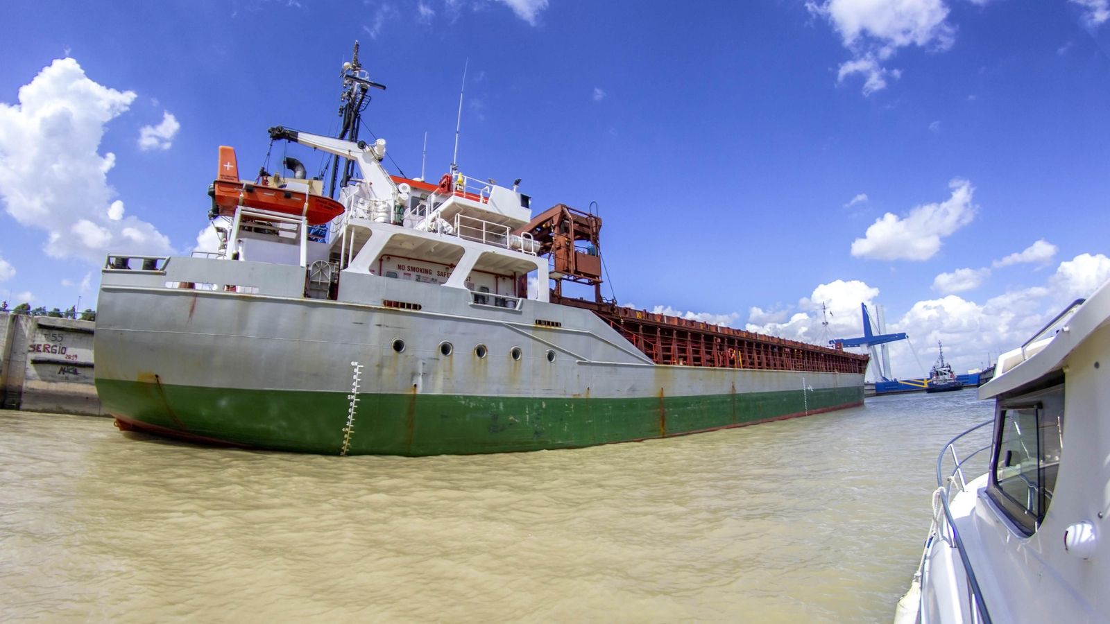 El barco de recreo comparte esclusa con un buque y un remolcador.