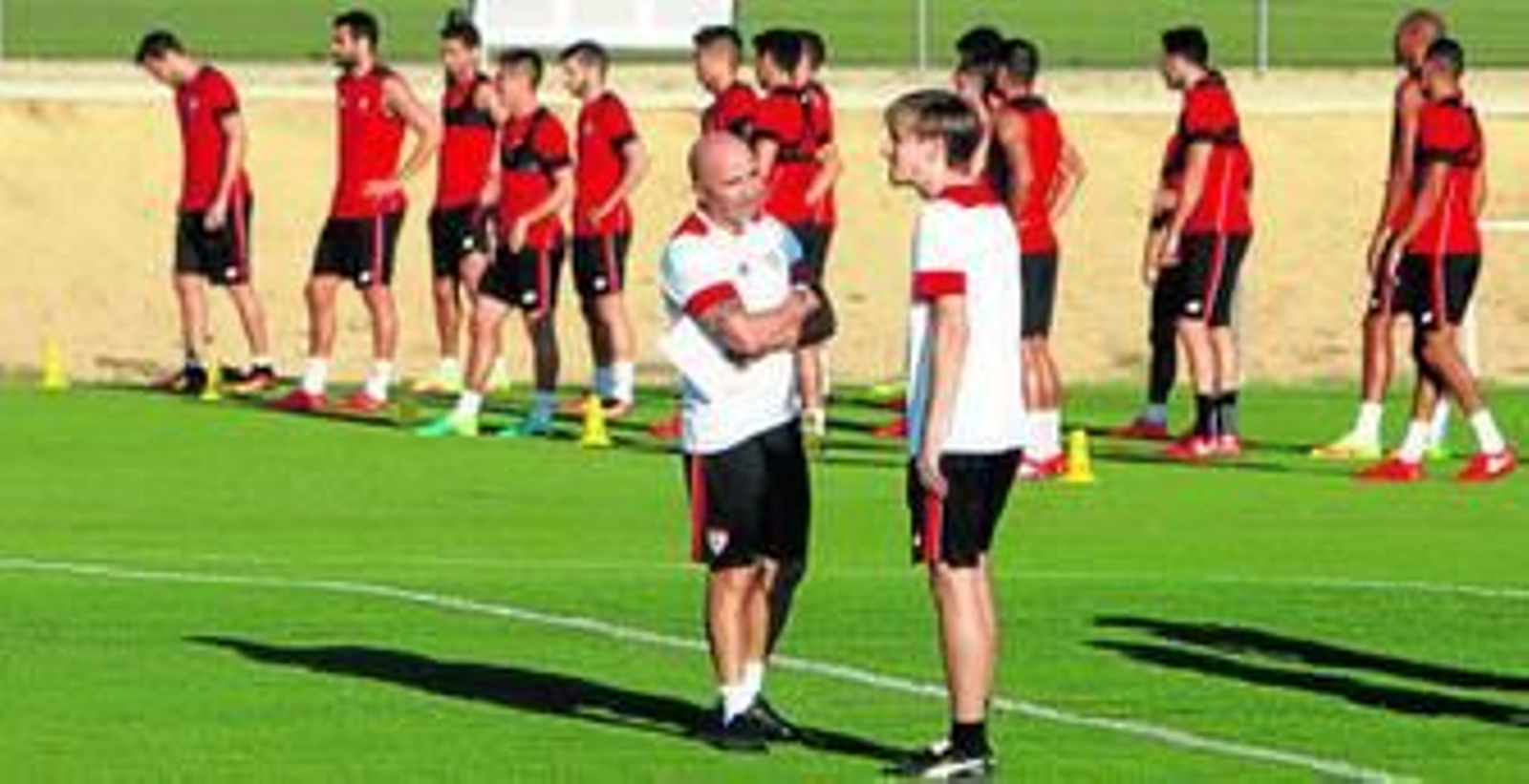 Jorge Sampaoli y Matías Manna, uno de sus ayudantes técnicos, dialogan con un grupo de jugadores al fondo.