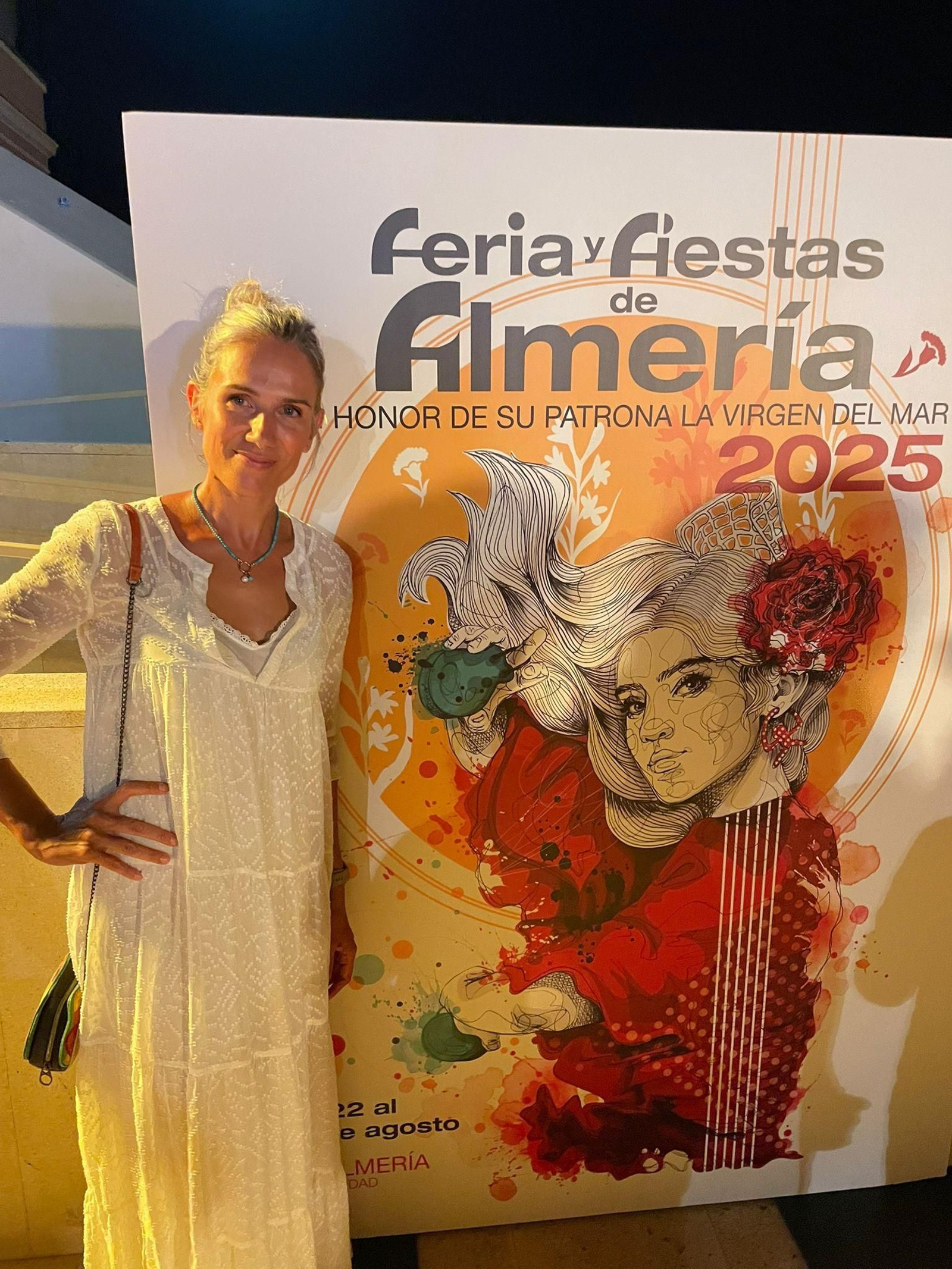 Mar Gregorio junto al cartel que ella misma ha diseñado para anunciar la Feria y Fiestas Mayores de Almería 2025