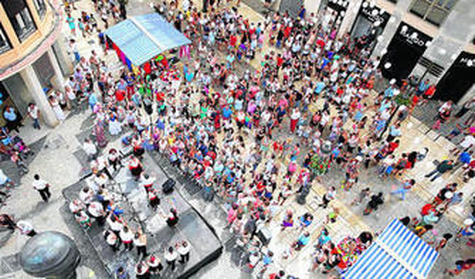 Desde un balcón se observa una panda de verdiales seguida por un buen número de parroquianos.