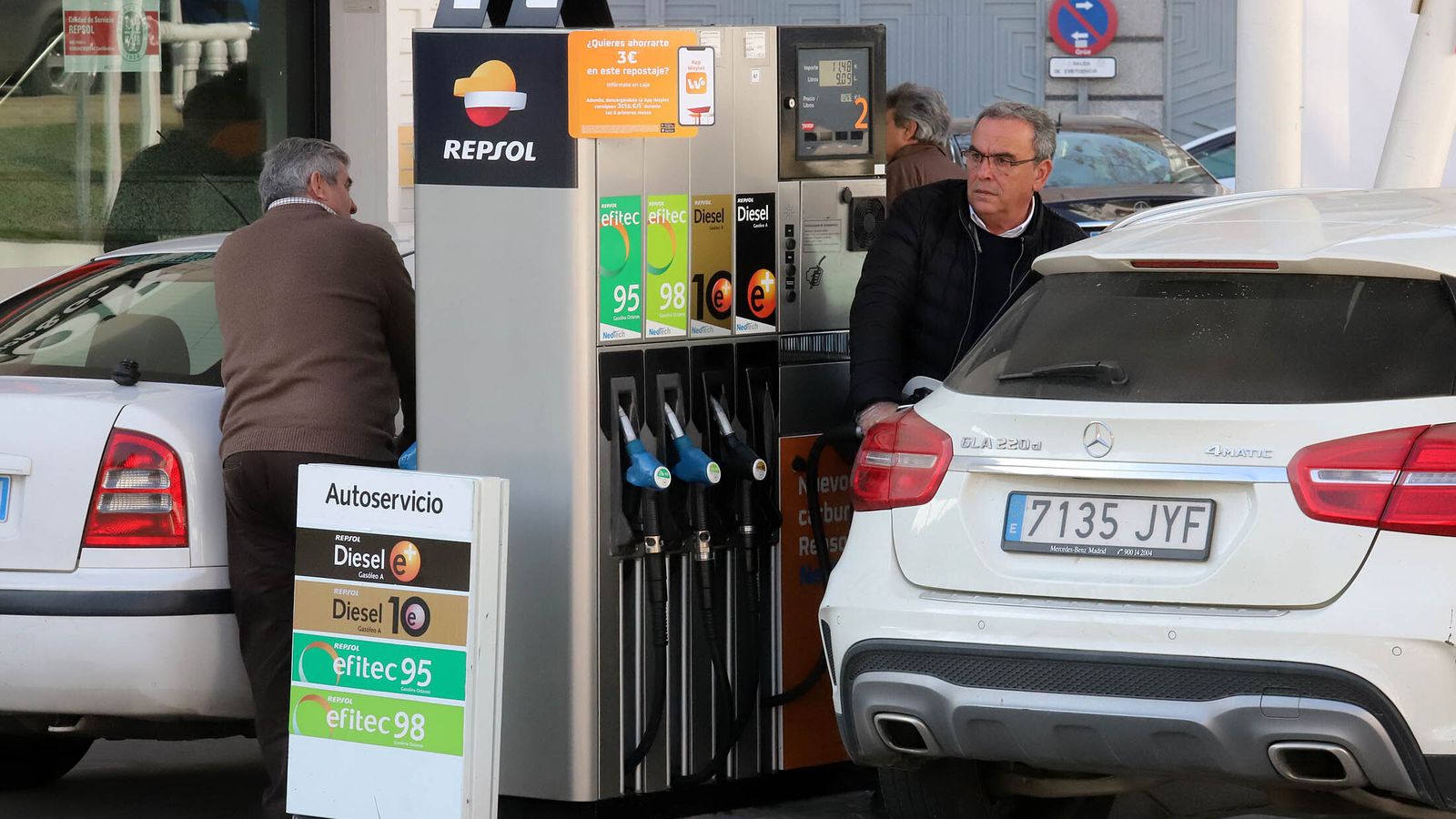 Dos hombres repostan combustible en una gasolinera