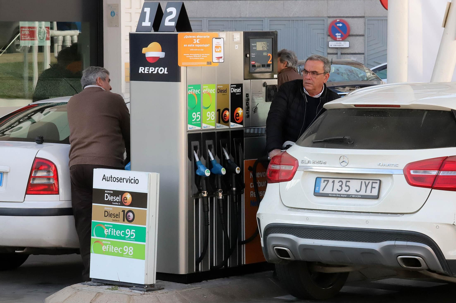 Dos hombres repostan combustible en una gasolinera
