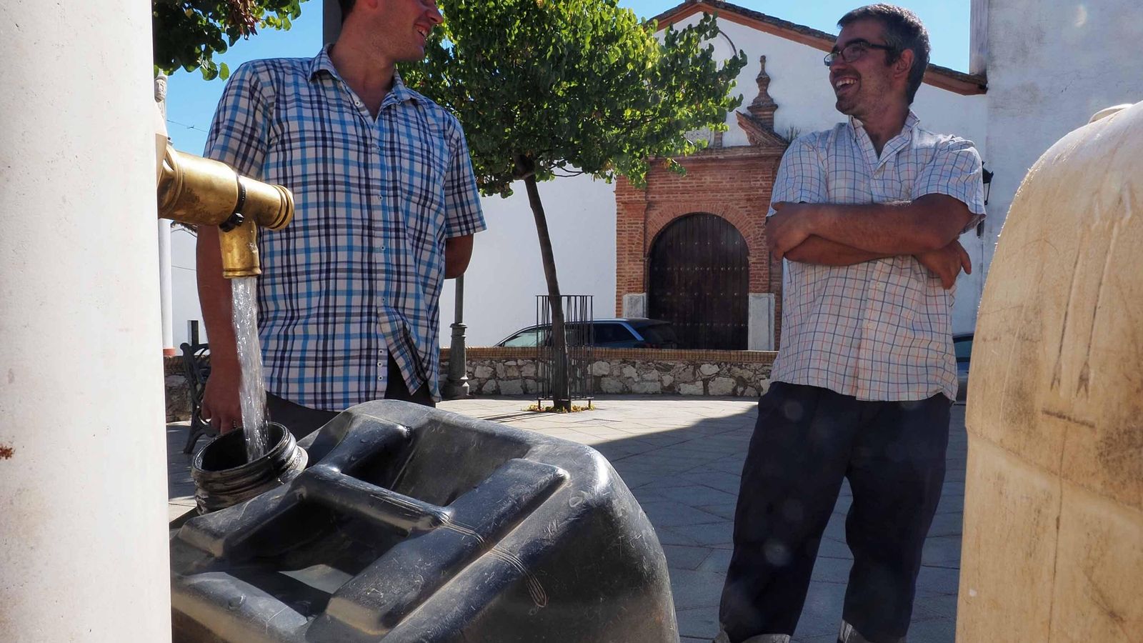 Los pequeños ganaderos Rafael Martín y Sergio Vázquez llenan garrafas de agua en Cortelazor para dar de beber a sus animales