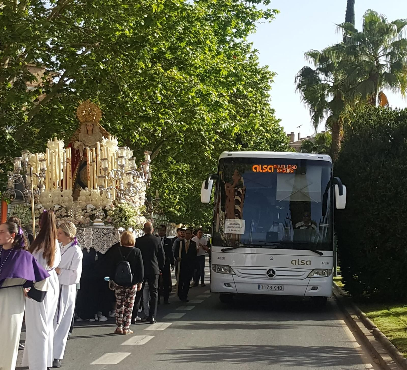 Imagen del paso de un autobús junto al cortejo de la procesión de la Hermandad de La Lanzada de Granada