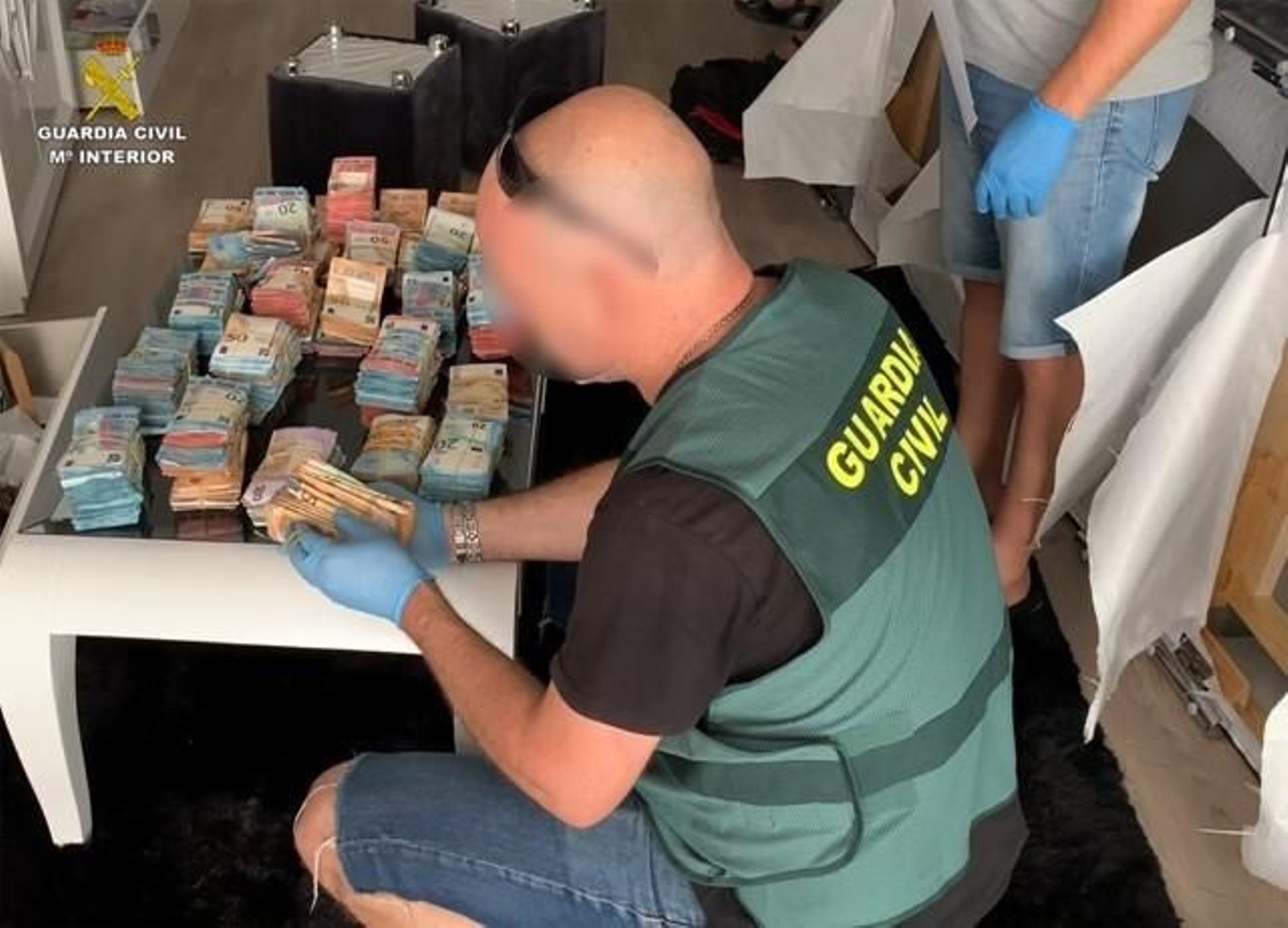 Un agente de la Guardia Civil junto a parte del dinero incautado. Un agente de la Guardia Civil junto a parte del dinero incautado.