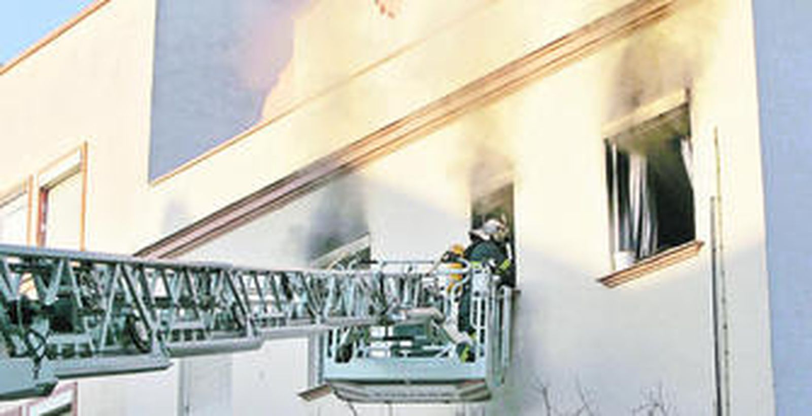 Los bomberos intentando entrar en la casa incendiada.