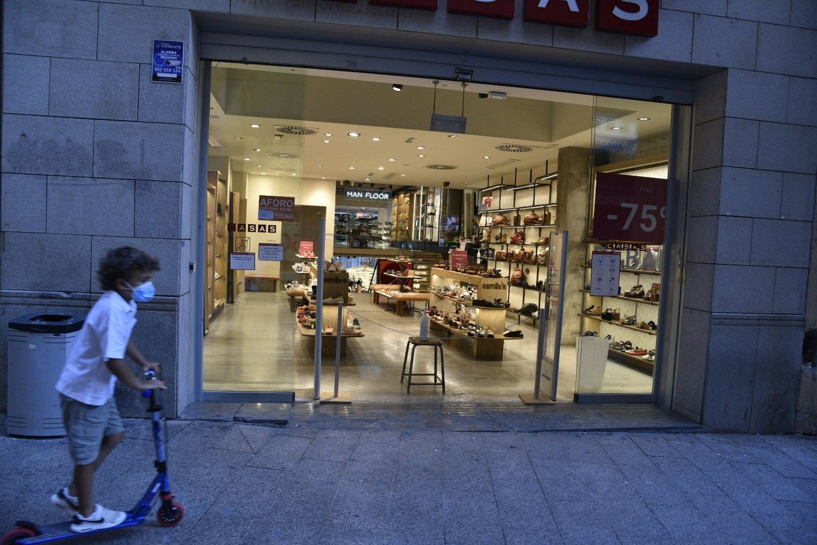 Un niño pasa con su patinete por una zona peatonal.
